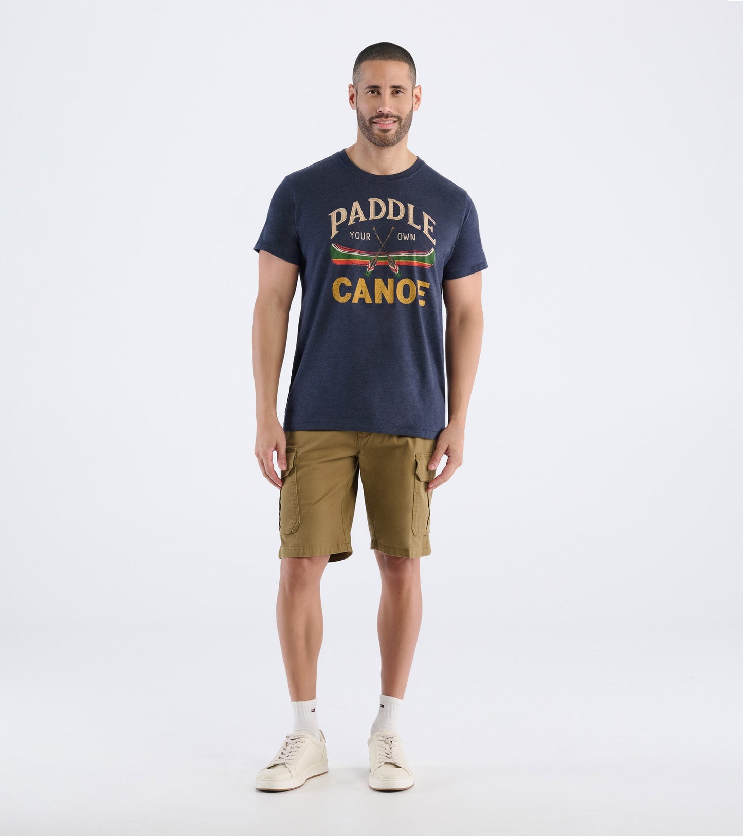 Navy blue men's t-shirt featuring a canoe graphic and text, paired with khaki shorts and white sneakers.