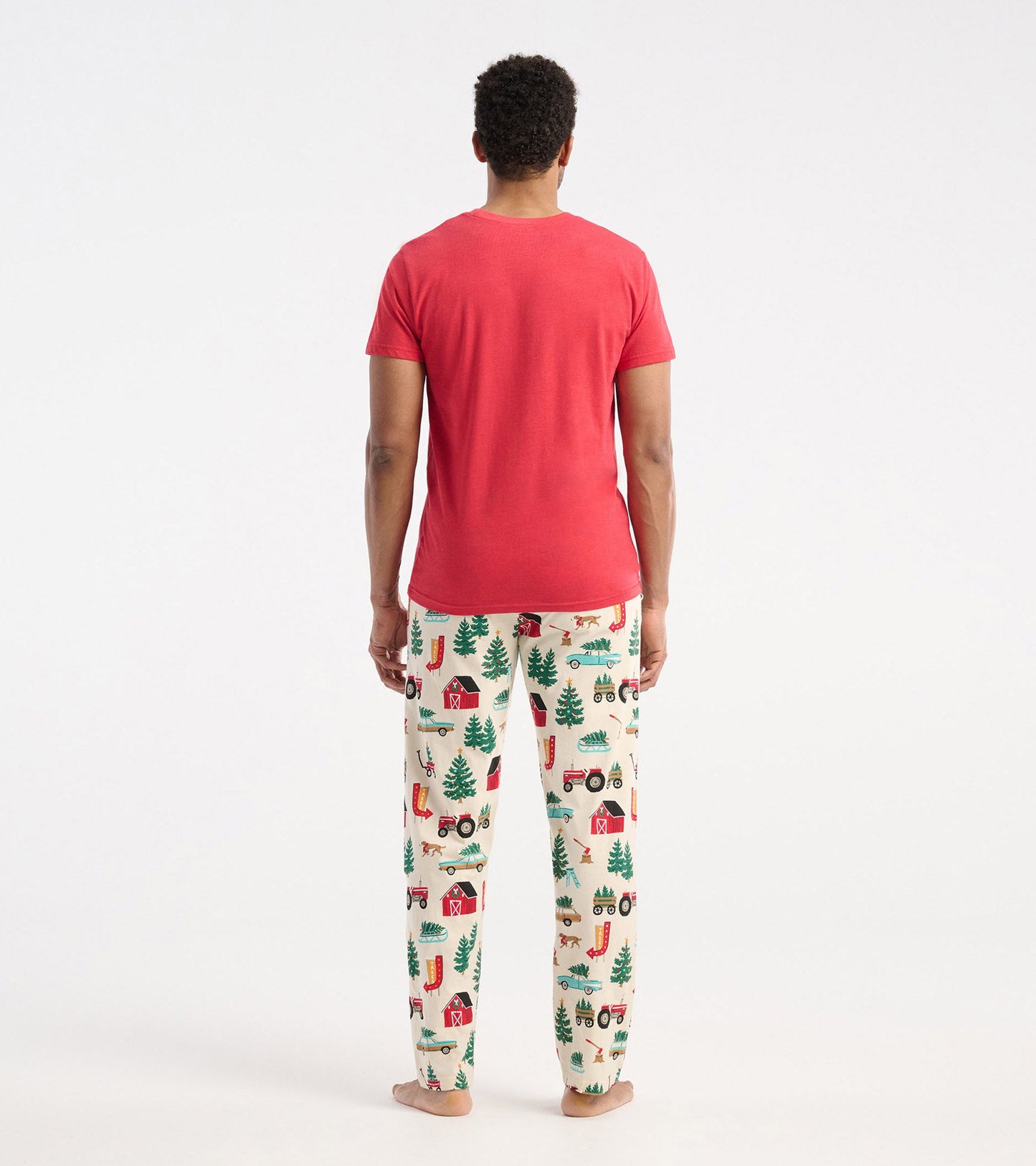 Red short-sleeve t-shirt worn with festive patterned pajama pants featuring trees, barns, and vehicles.