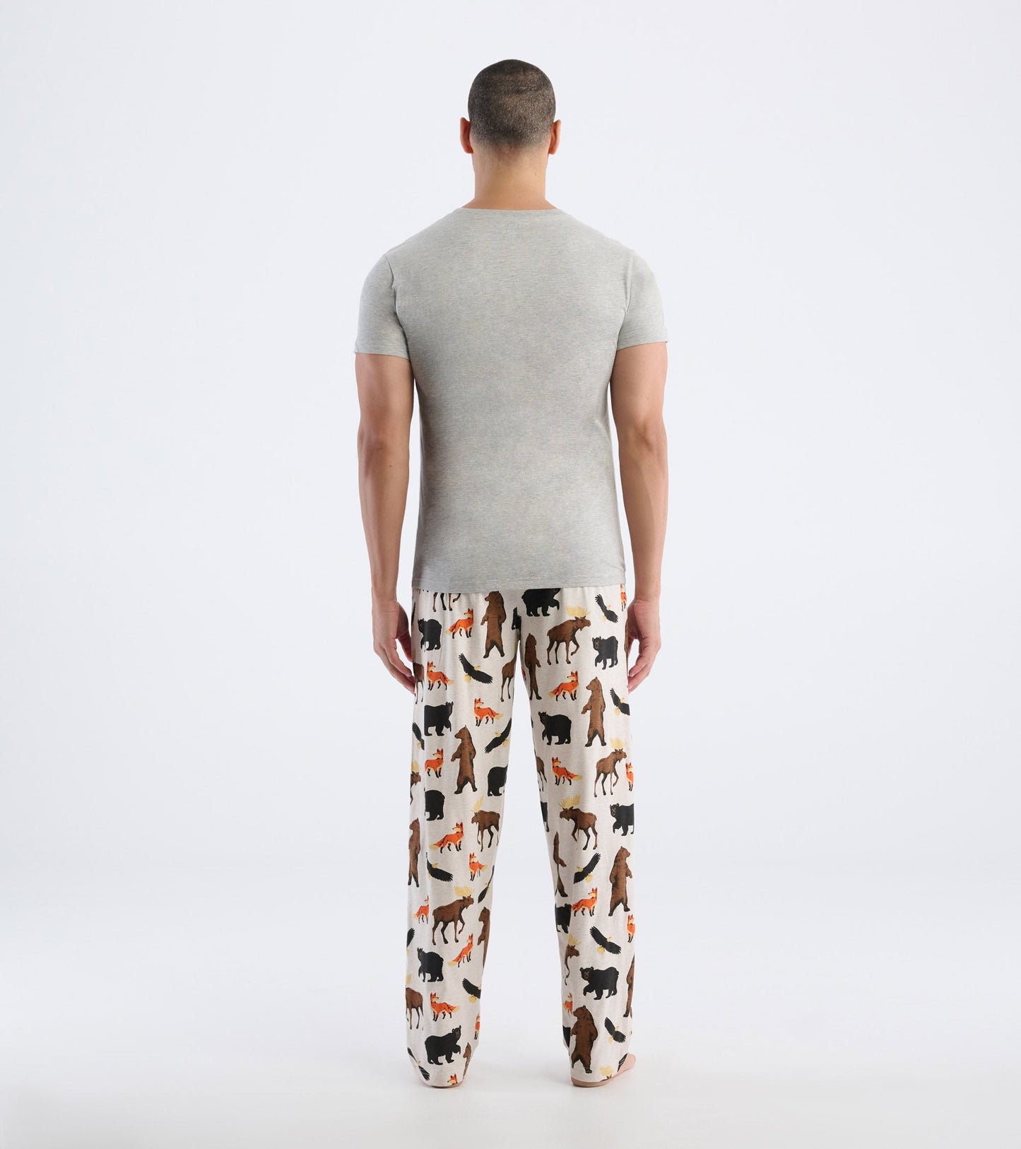 Gray short-sleeve tee worn with patterned pajama pants featuring various wildlife silhouettes. View from the back.