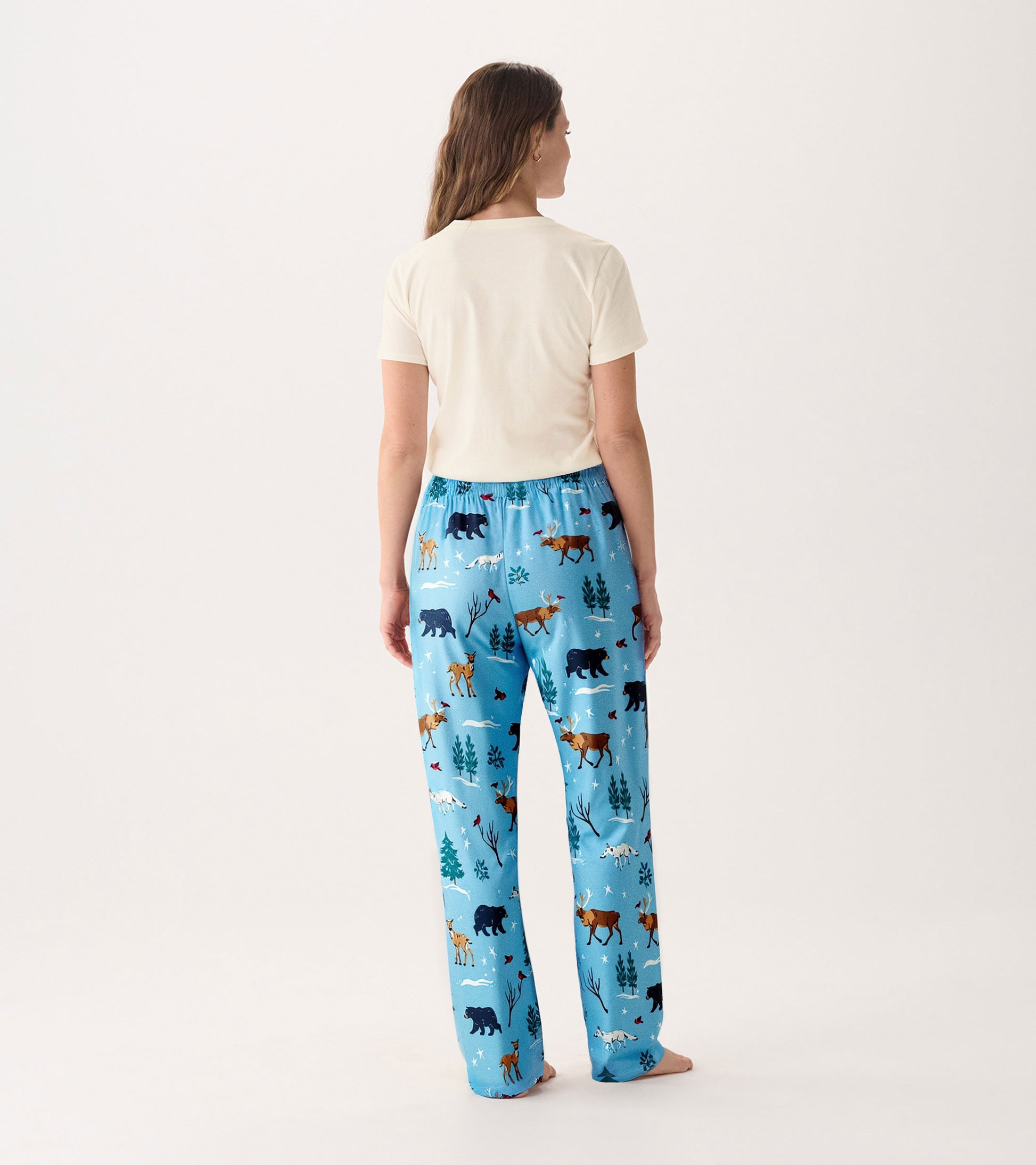 Light cream short-sleeve pajama t-shirt paired with blue pants featuring a wildlife print of bears and trees.