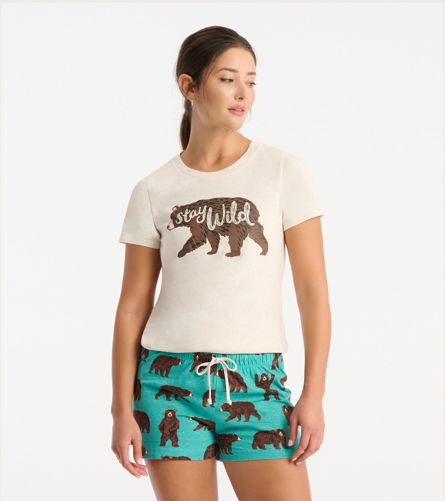 Cream short-sleeve pajama t-shirt featuring a brown bear graphic and the text "Stay Wild." Paired with teal shorts with bear…