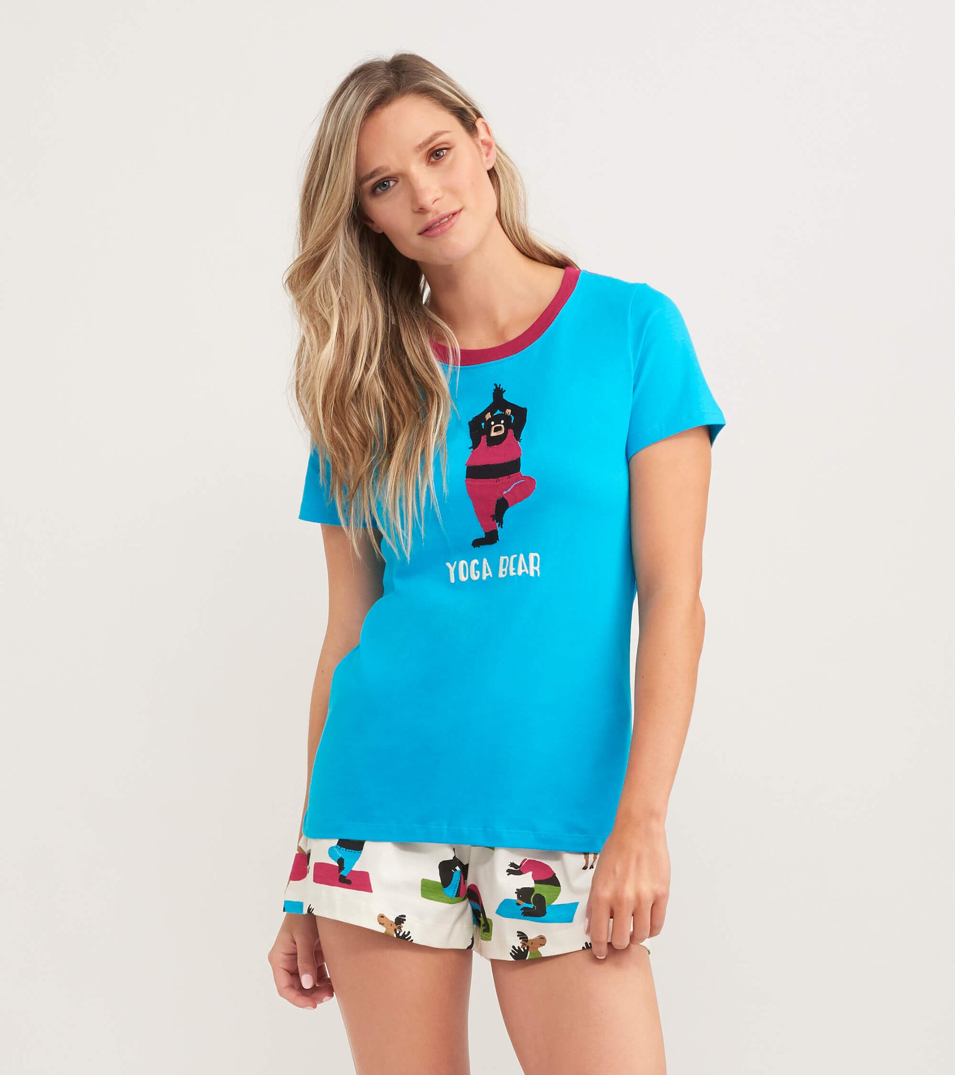 Turquoise women's pajama t-shirt featuring a bear in a yoga pose and a contrasting neckline, paired with patterned shorts.