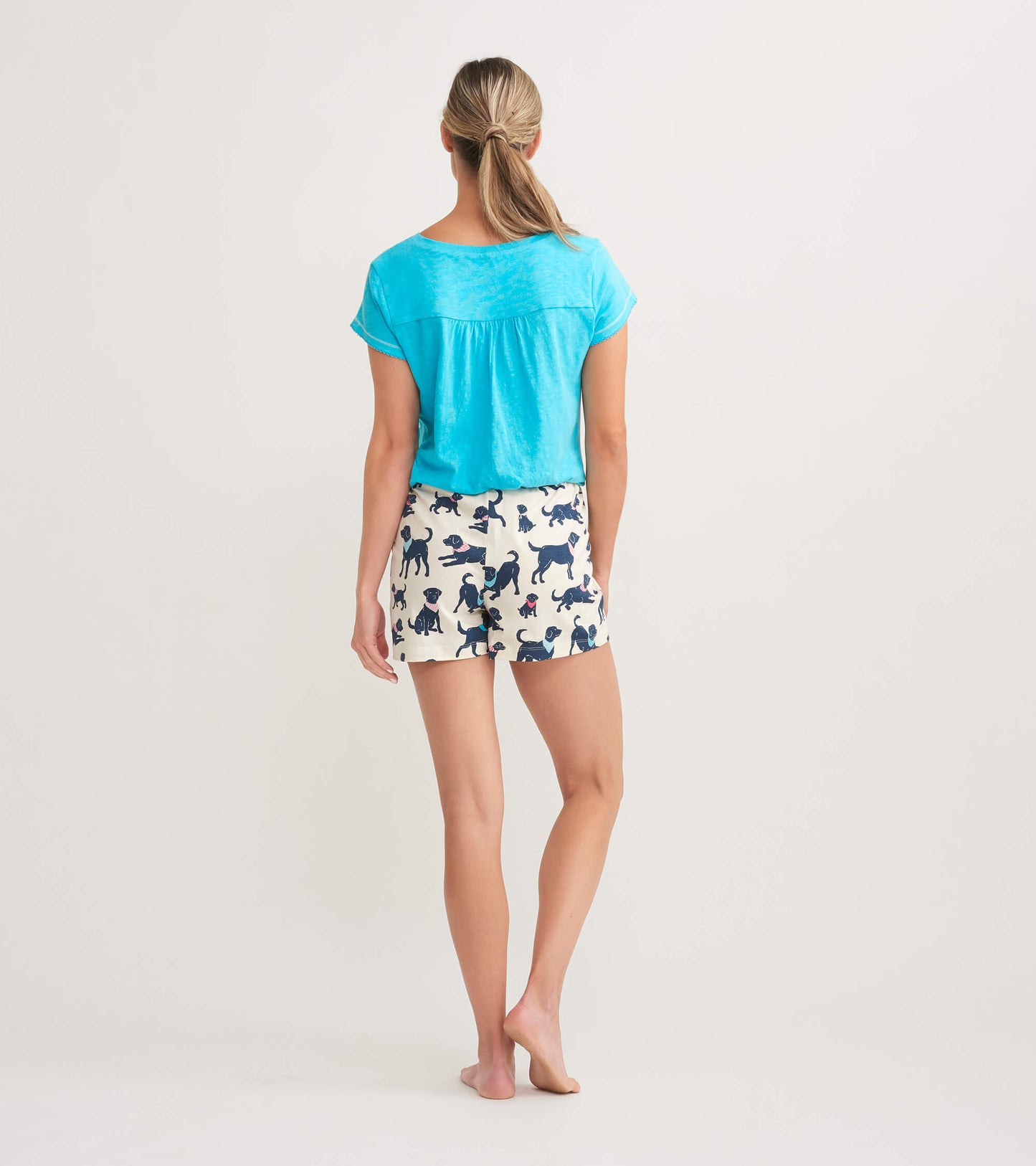 Light blue women's V-neck tee paired with patterned shorts featuring various dog illustrations, viewed from the back.