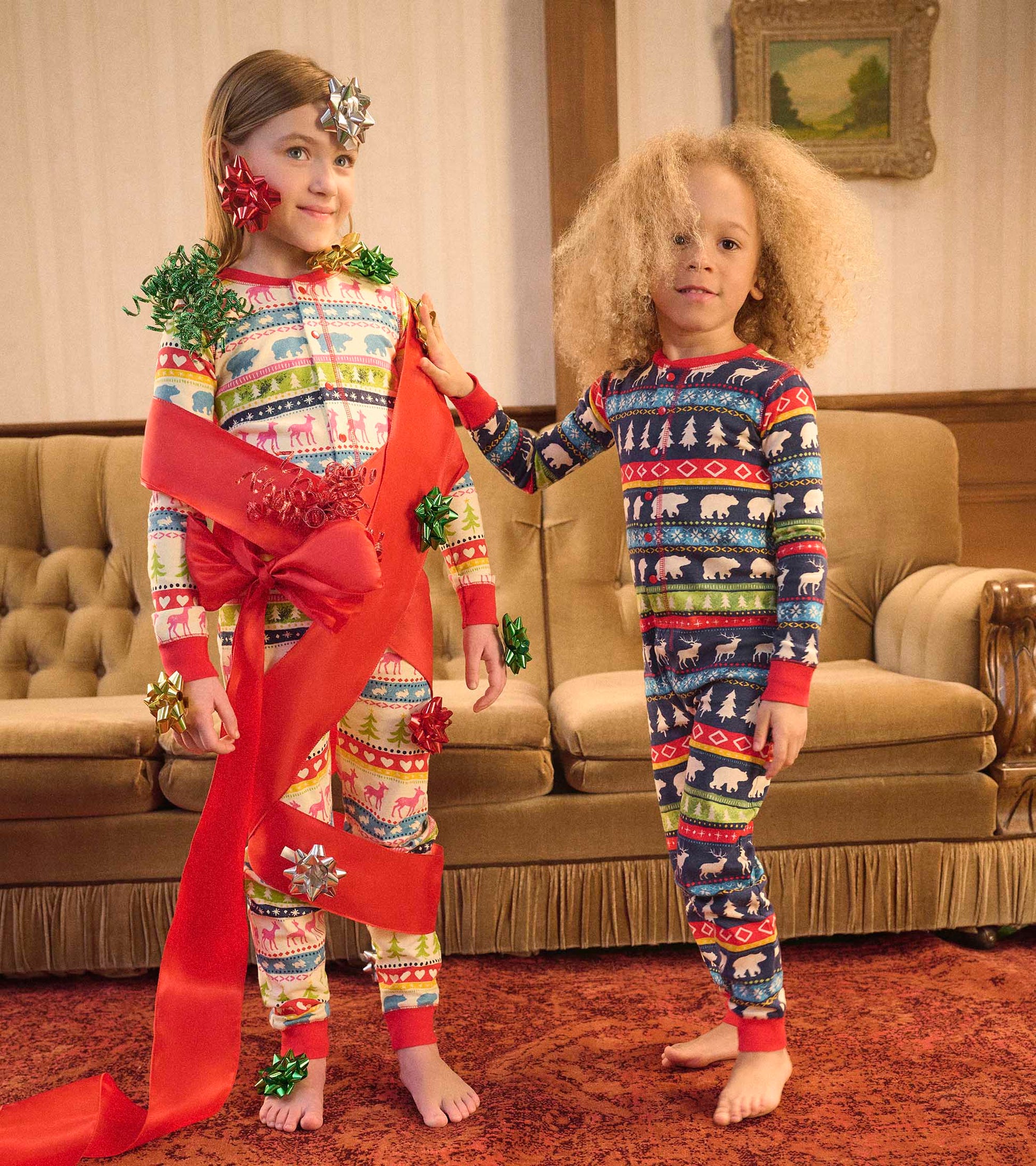 Navy Fair Isle onesie featuring festive patterns, worn by two kids adorned with holiday decorations in a cozy setting.