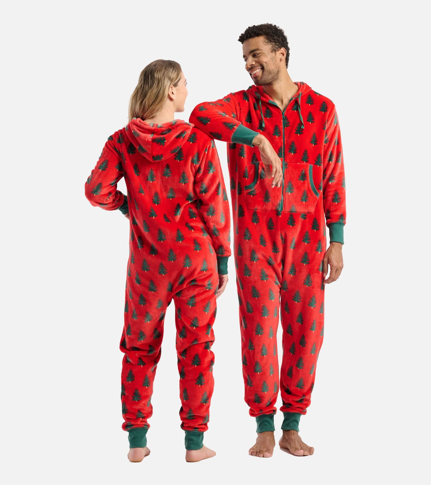 Red fleece jumpsuit with green tree pattern, featuring a hood and front pockets, shown on two models from the back and side.