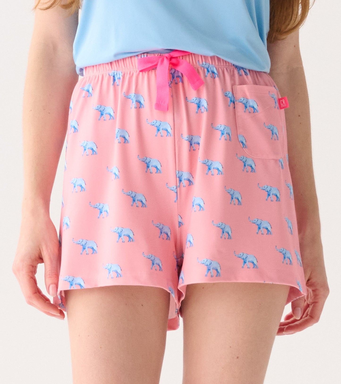 Pink pajama shorts featuring a playful blue elephant pattern, with an elastic waistband and a front pocket.