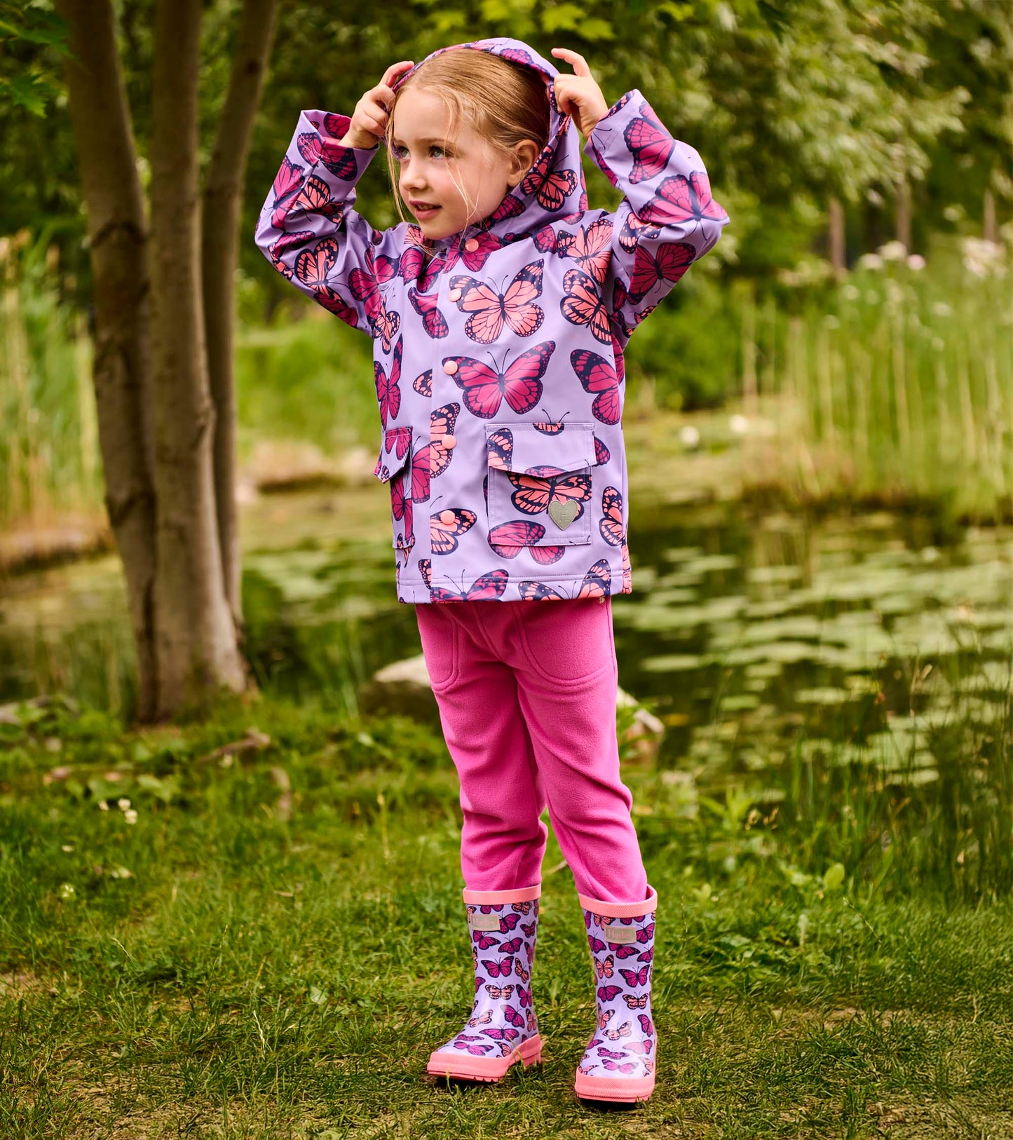 Girls lavender rain jacket with pink butterfly print, hood, snap front, and flap pockets, front view