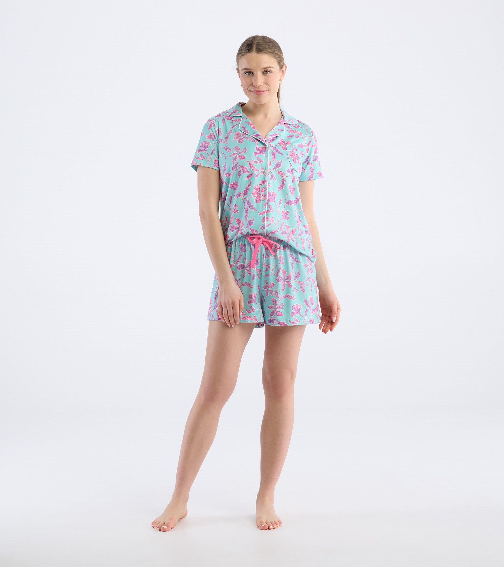 Turquoise short pajama set featuring pink batik flower patterns, with a short-sleeve top and drawstring shorts.