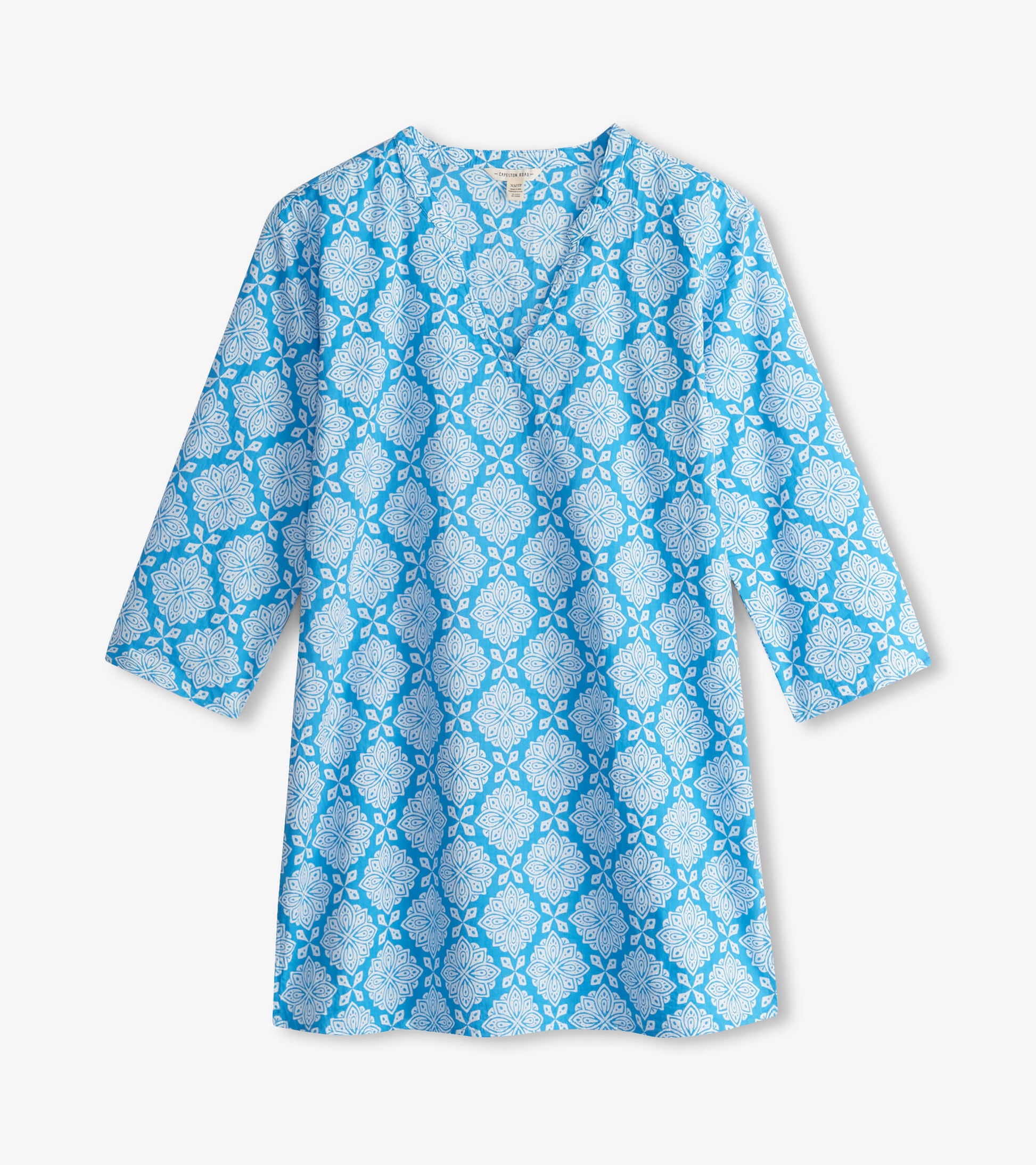 Blue tunic featuring a white floral pattern and a V-neckline, with three-quarter sleeves.