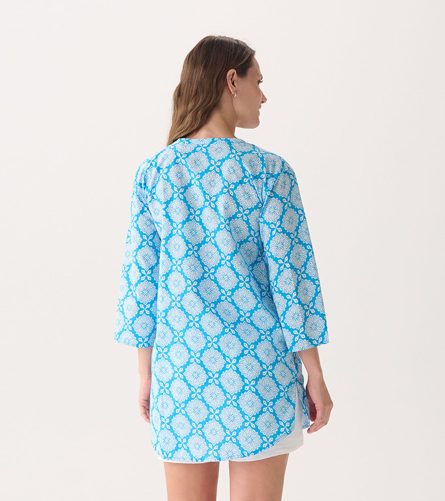 Light blue tunic with a white floral pattern, featuring three-quarter sleeves and a relaxed fit, shown from the back.