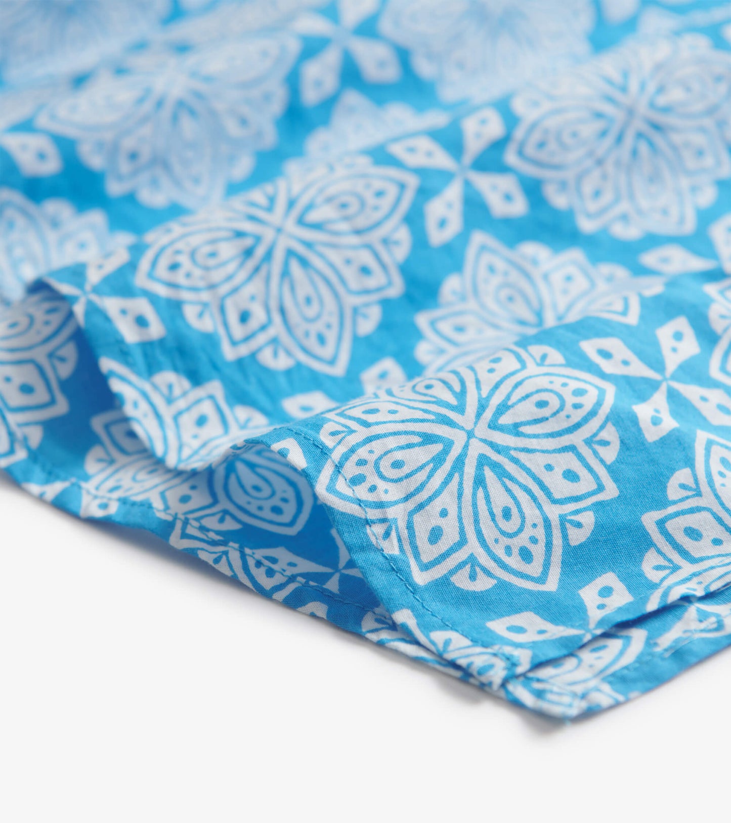 Blue tunic featuring a white floral pattern, made from lightweight fabric, ideal for casual wear.