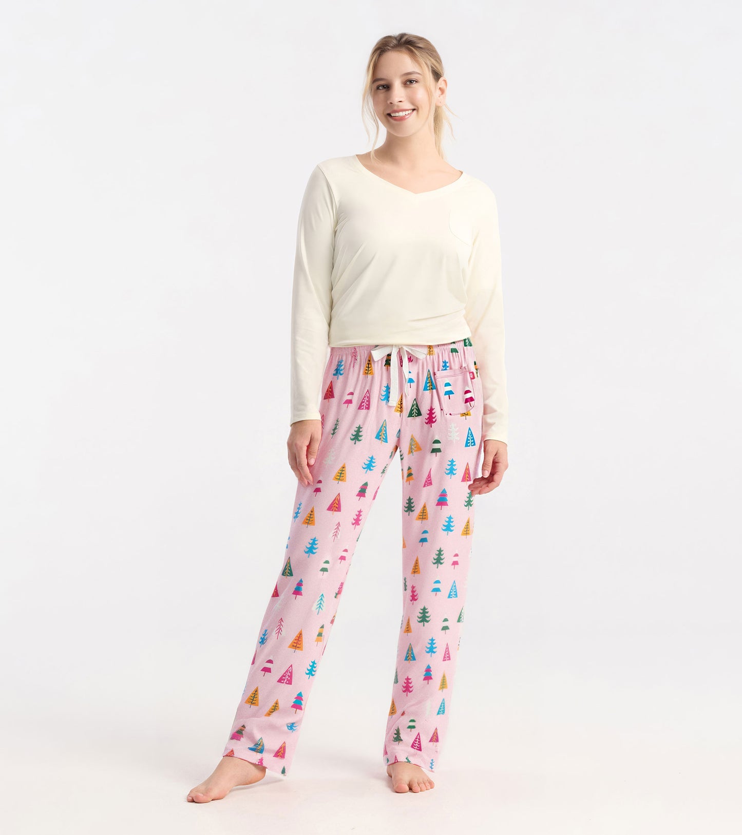 Light pink pajama pants featuring colorful holiday tree patterns, made from soft polyknit fabric, with an elastic waistband.