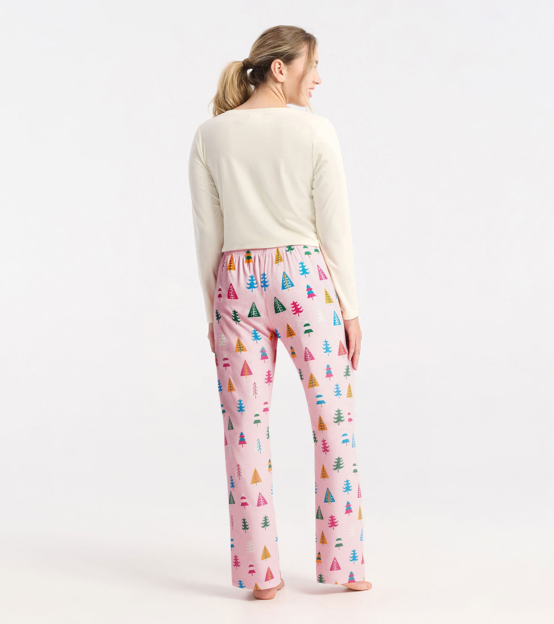 Colorful pajama pants featuring a holiday tree pattern on a pink background, made from soft polyknit fabric.