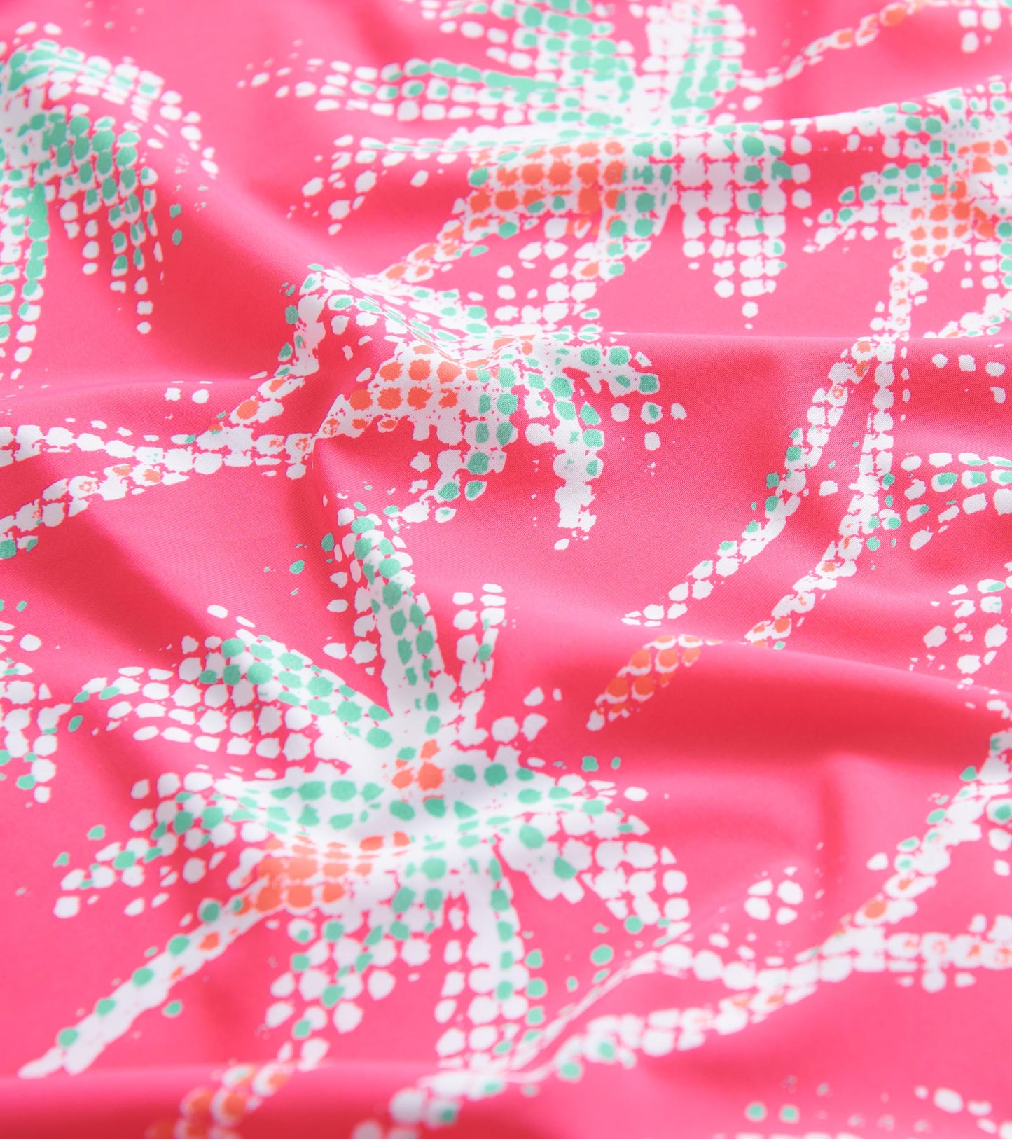 Pink fabric featuring a palm leaf pattern in white, green, and orange, ideal for summer wear.
