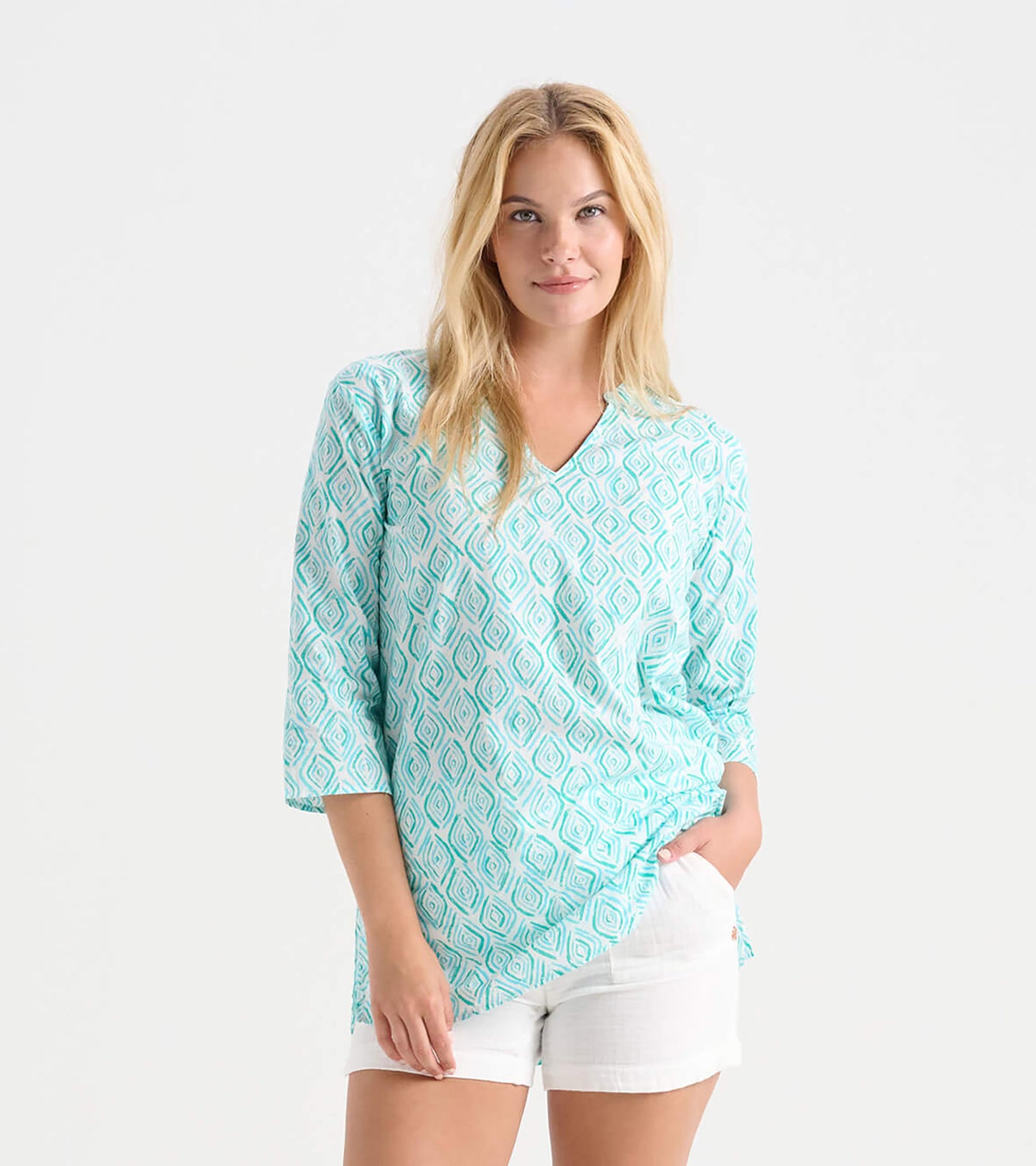 Turquoise tunic with diamond pattern, V-neck, and three-quarter sleeves, styled with white shorts.