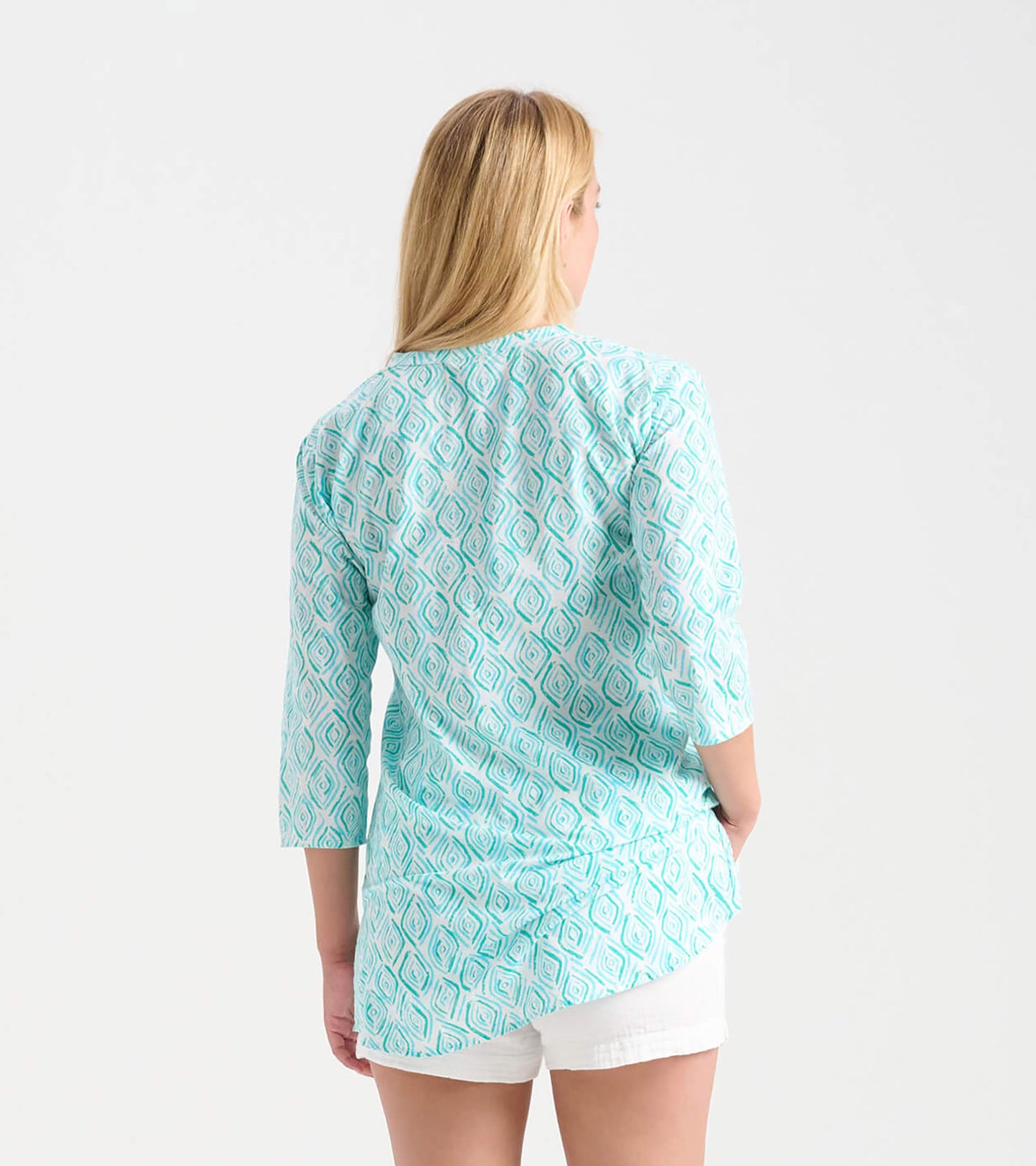 Light turquoise tunic with a geometric pattern, featuring three-quarter sleeves and a curved hem, worn with white shorts.