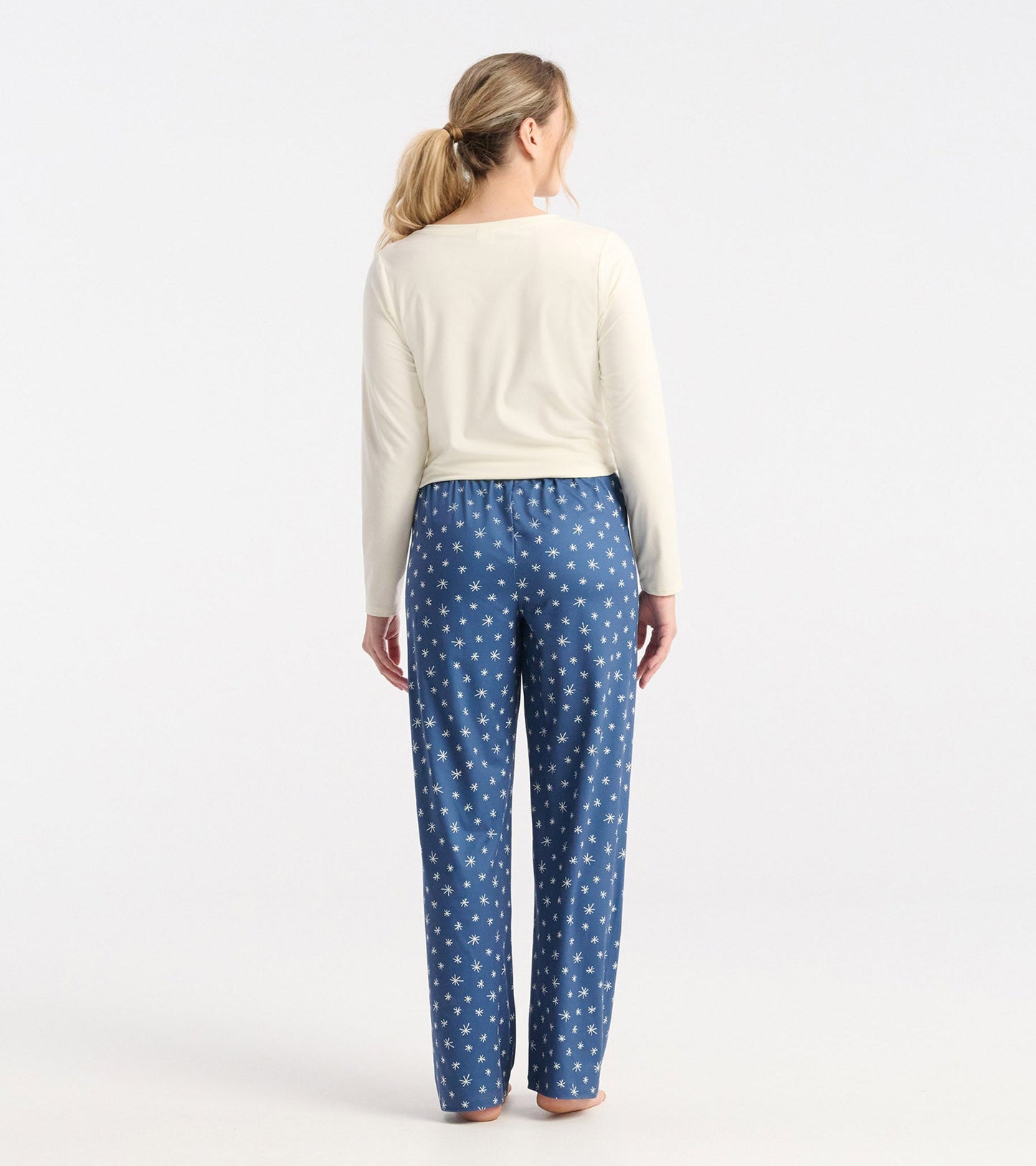 Blue polyknit pajama pants featuring a white snowflake pattern, shown from the back with an elastic waistband.