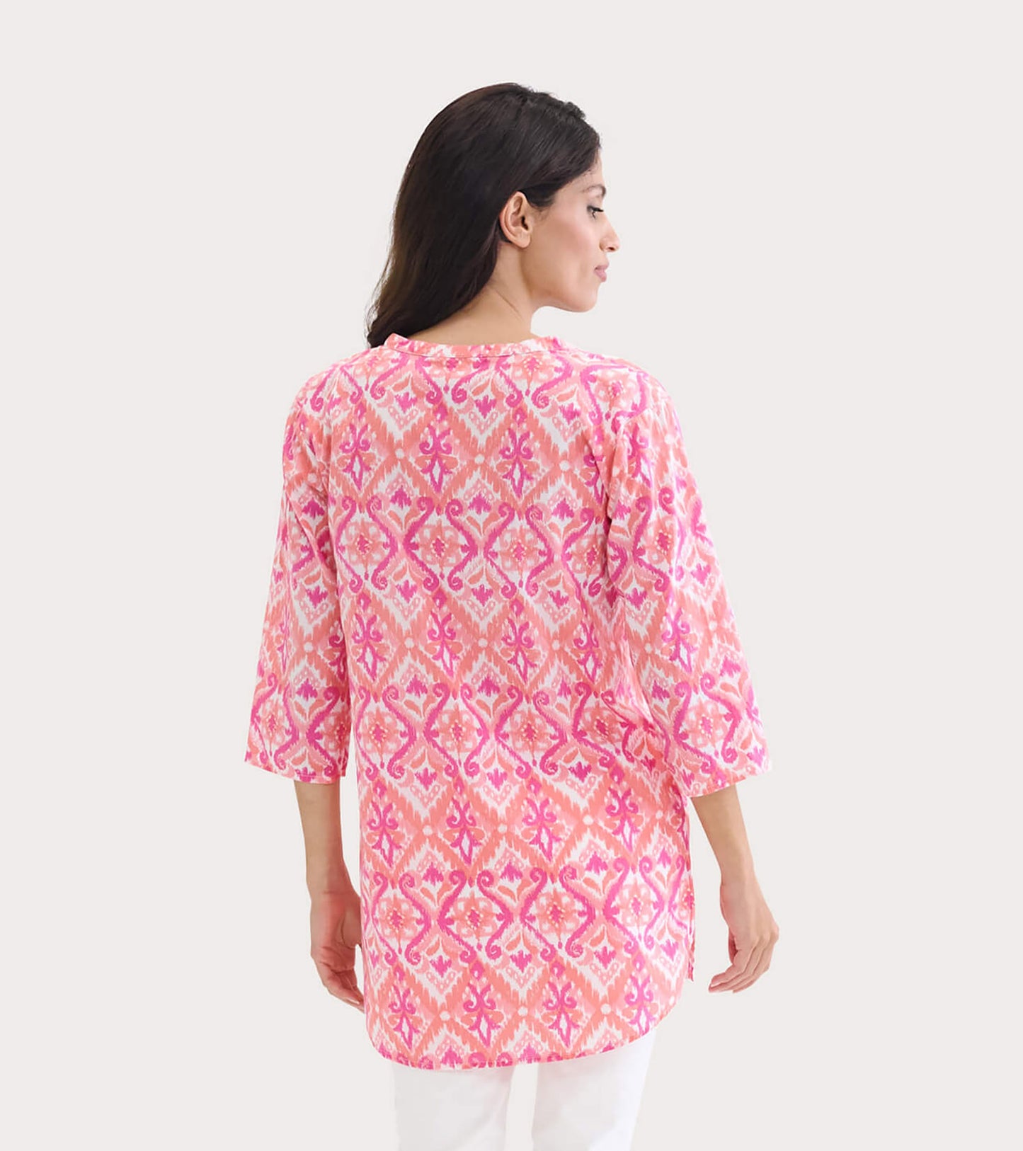 Back view of a women's tunic featuring a pink and orange ikat pattern with three-quarter sleeves.