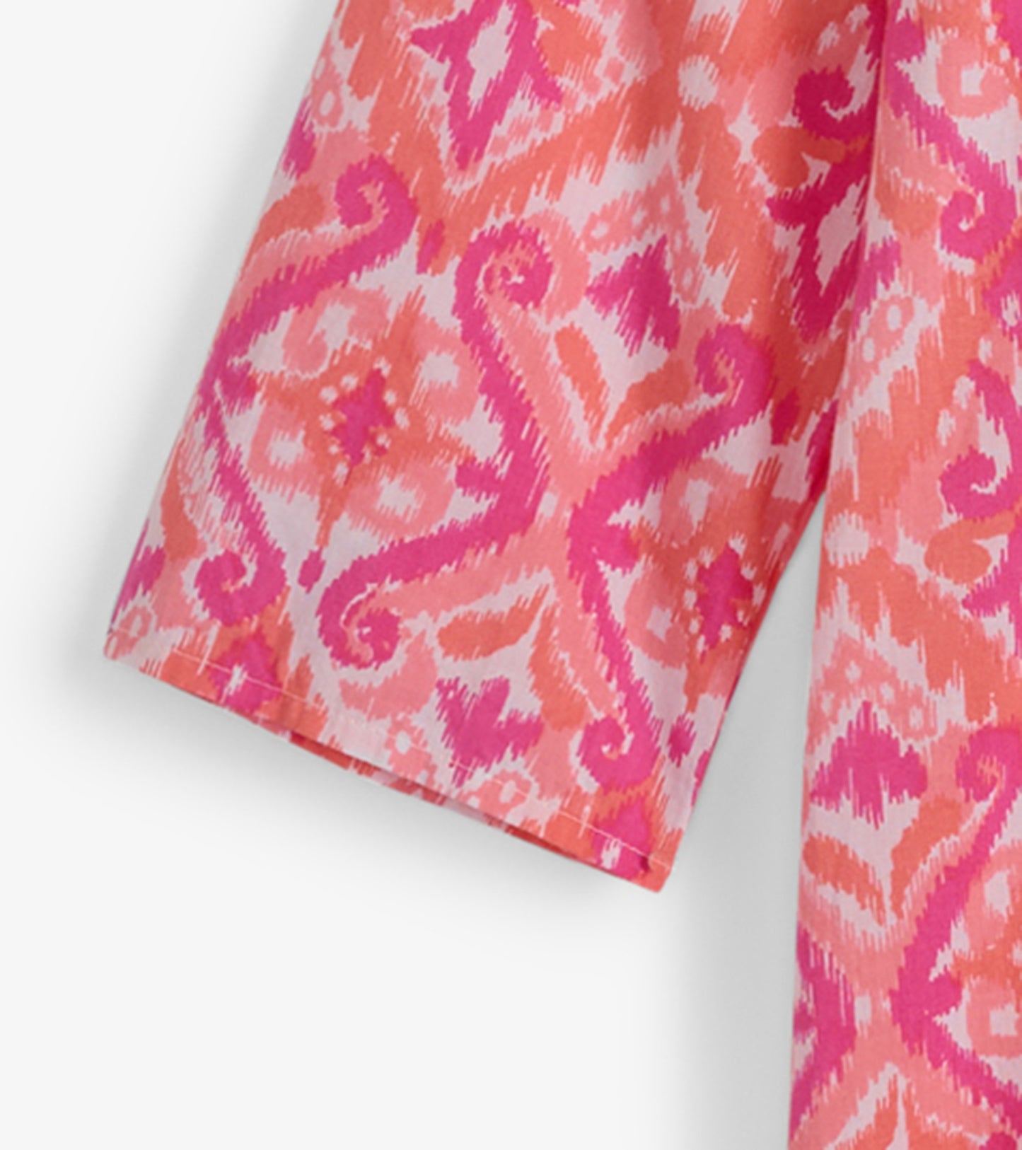 Pink and coral tunic featuring an ikat pattern, with short sleeves and a relaxed fit. Ideal for casual beach outings.