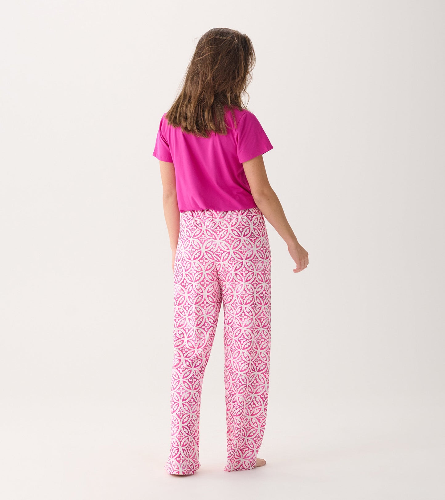 Back view of women's pink pajama pants featuring a lotus mandala pattern, paired with a solid pink top.