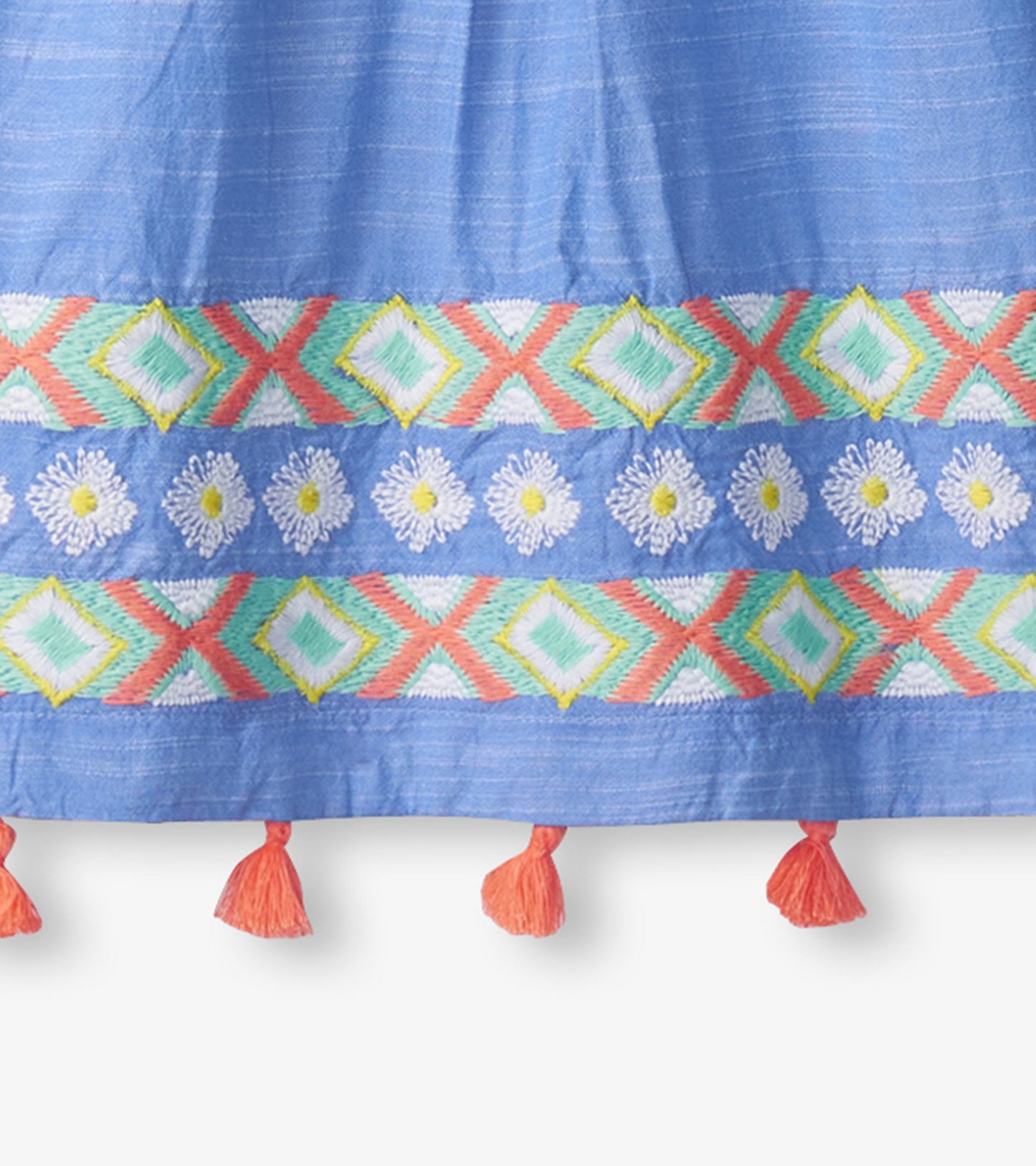 Light blue chambray dress featuring colorful embroidered patterns and decorative tassels at the hem.