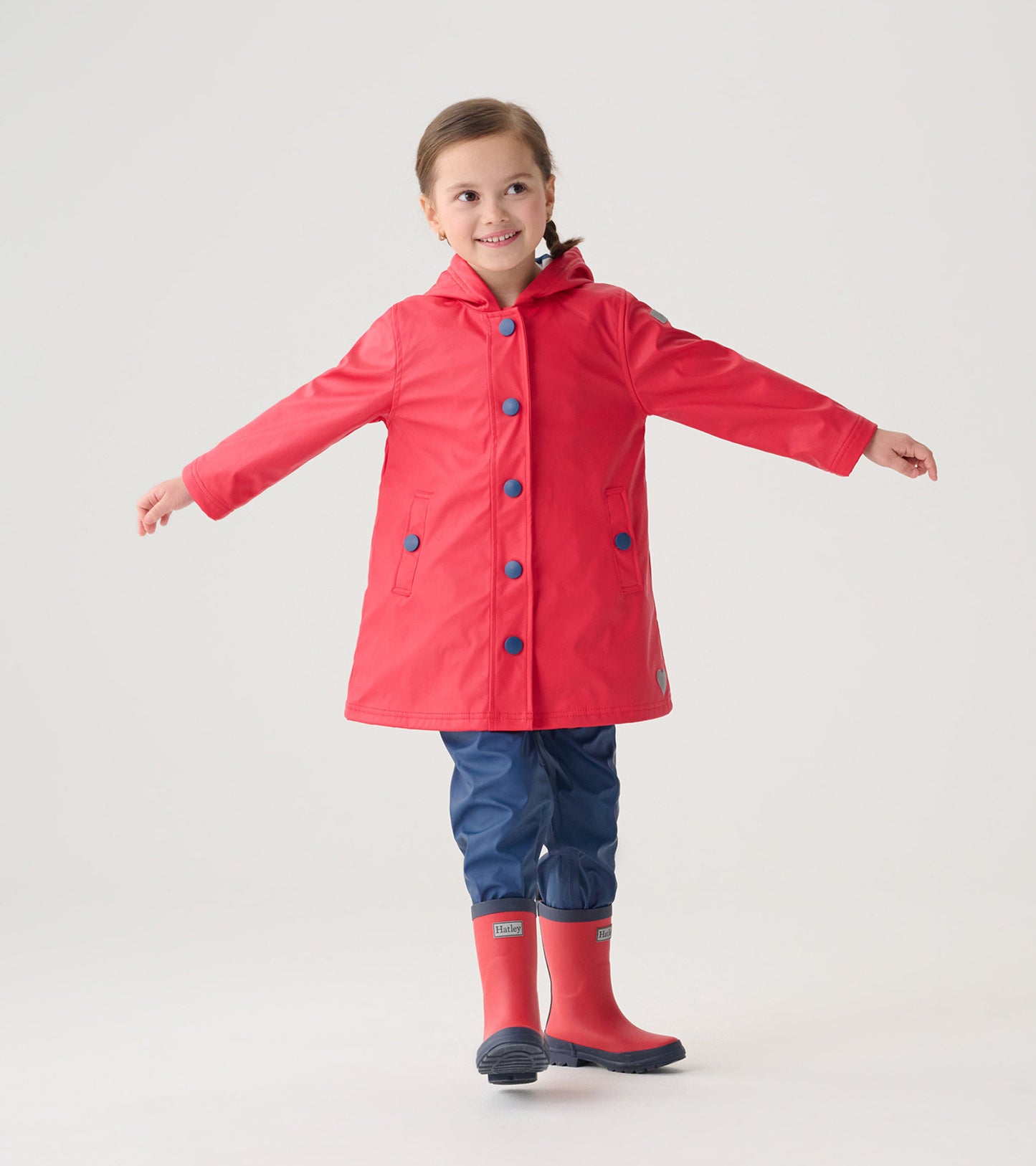Red and navy button-up rain jacket with a hood, featuring blue buttons, worn by a smiling girl.