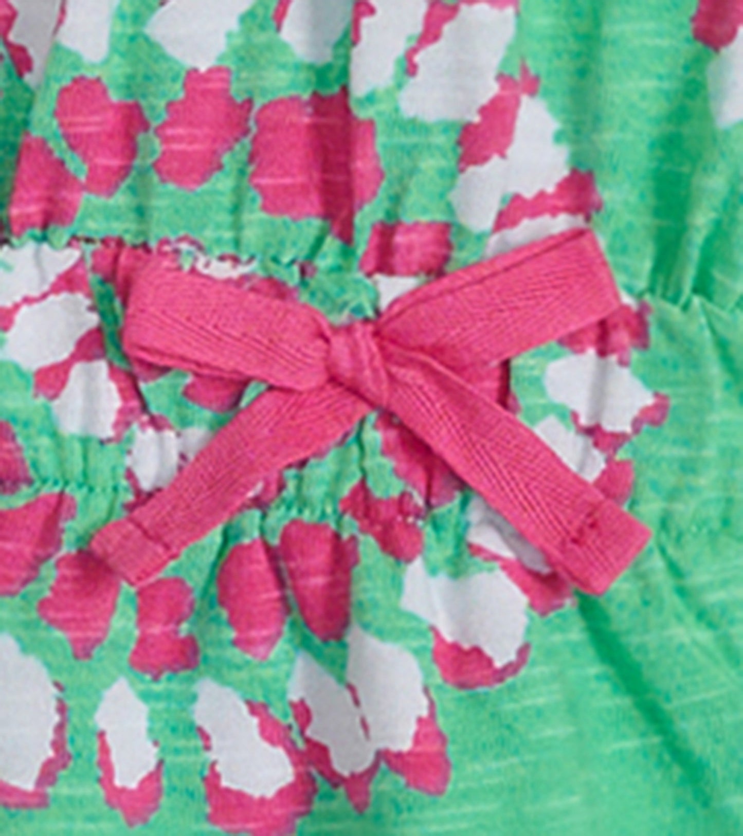 Green t-shirt dress featuring a colorful mandala pattern and a pink bow at the waist. Suitable for girls.