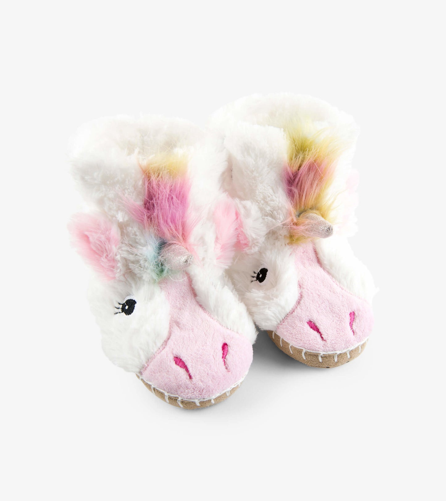 White fuzzy unicorn slippers with pink accents and colorful mane, designed for kids' comfort and warmth.