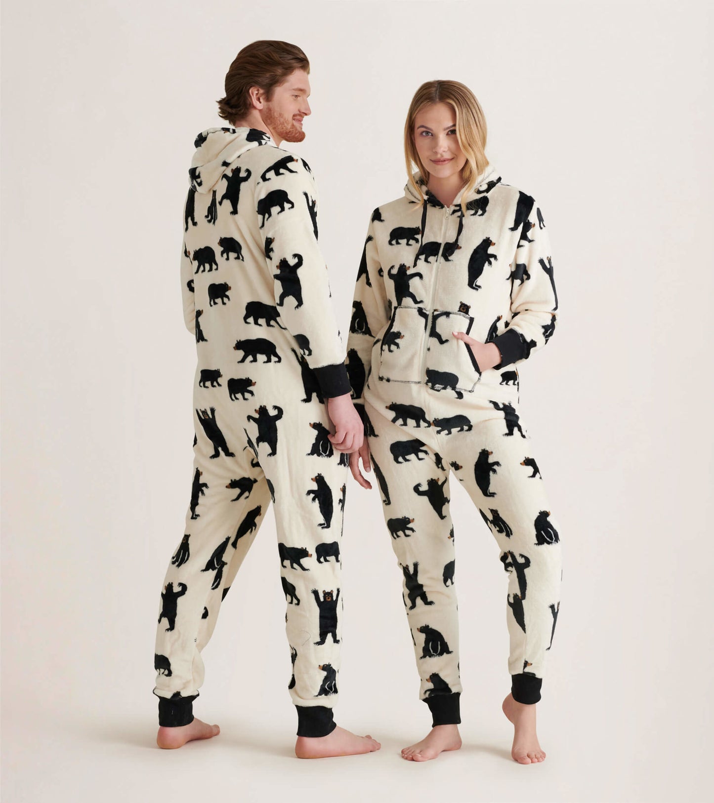 Hooded fleece jumpsuit in cream with black bear patterns, featuring a front pocket and ribbed cuffs.