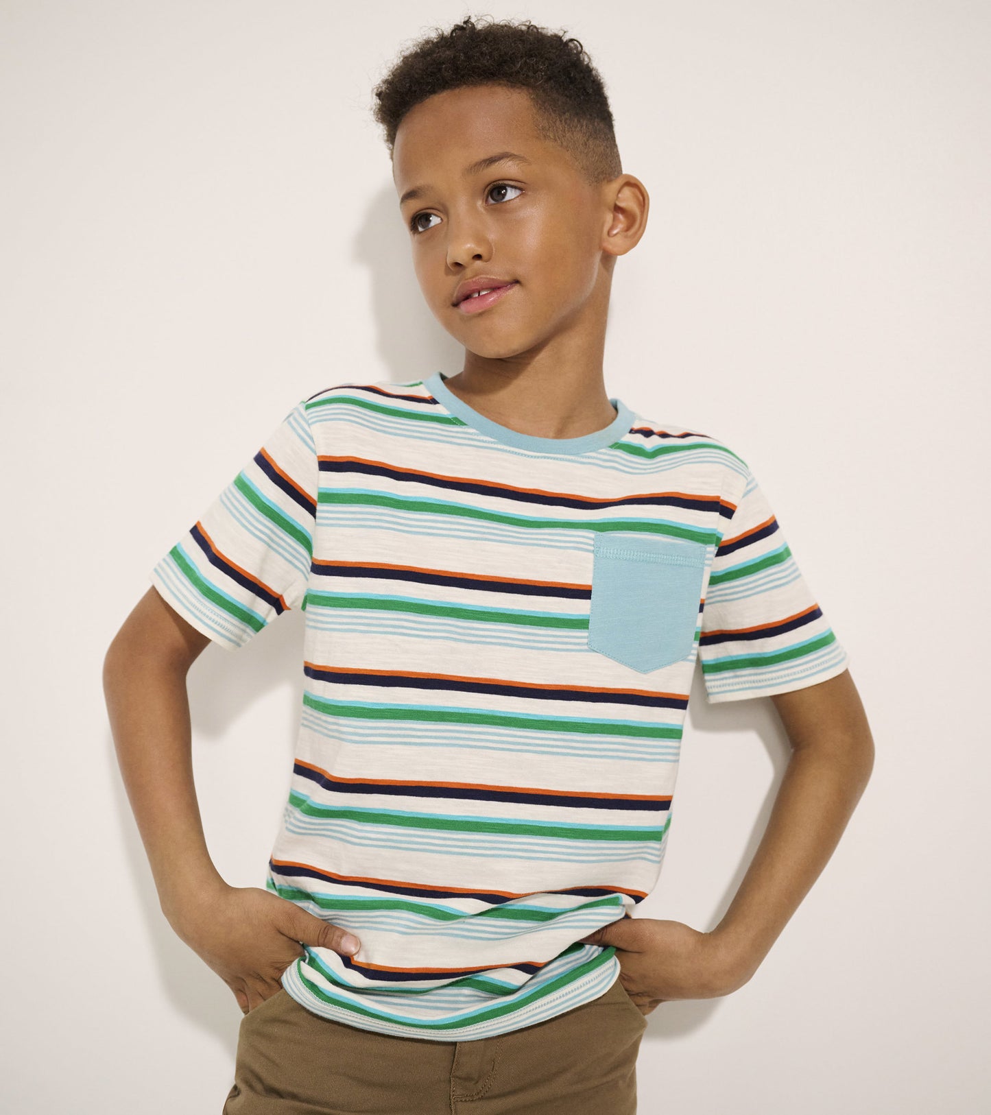 Striped short-sleeve tee featuring green, orange, and navy lines with a light blue pocket, perfect for outdoor activities.