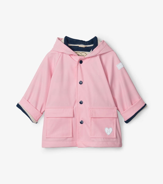 Pink baby raincoat with a hood, front buttons, and two pockets, featuring navy blue trim on sleeves.