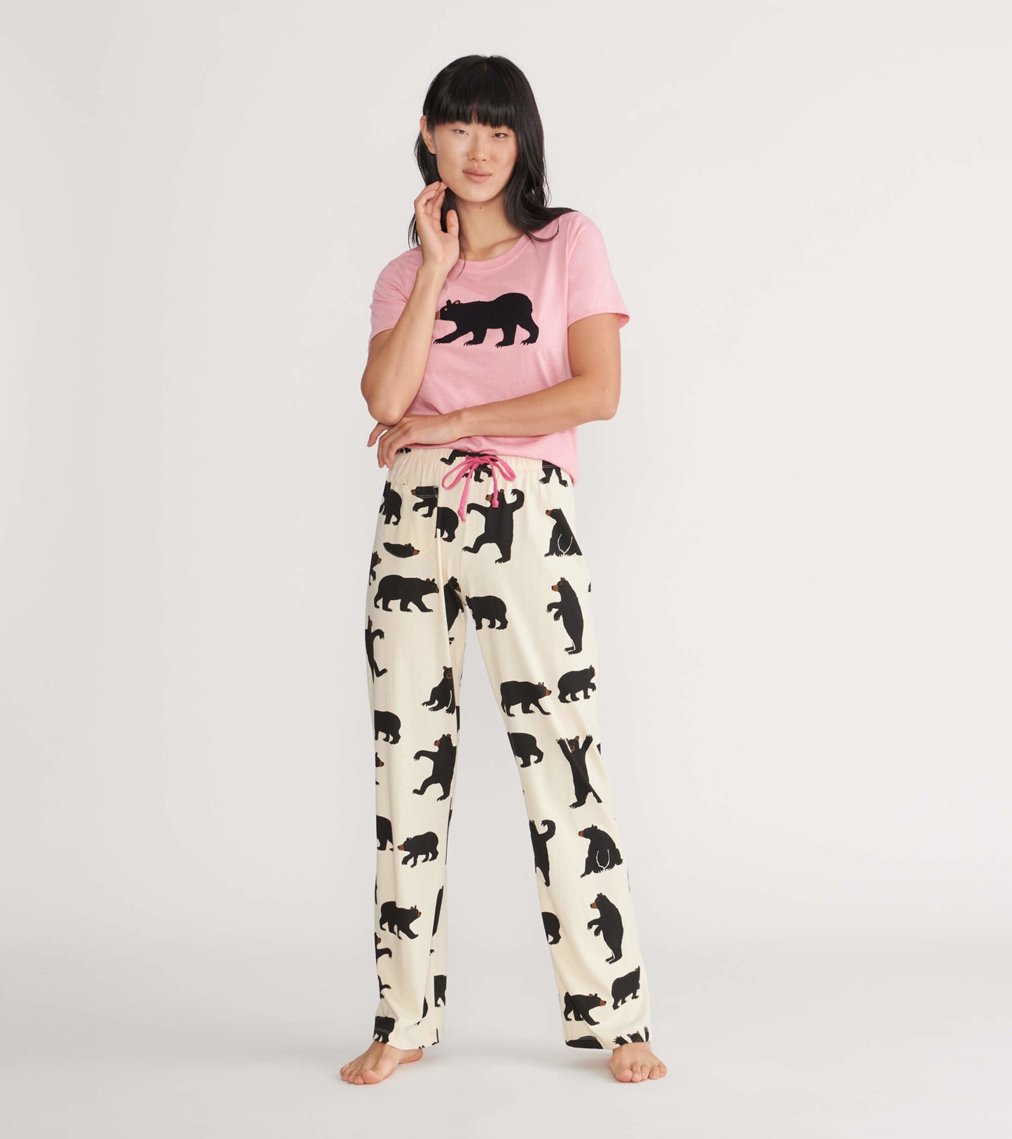 Pink women's pajama t-shirt featuring a black bear graphic, paired with cream pants adorned with black bear silhouettes.