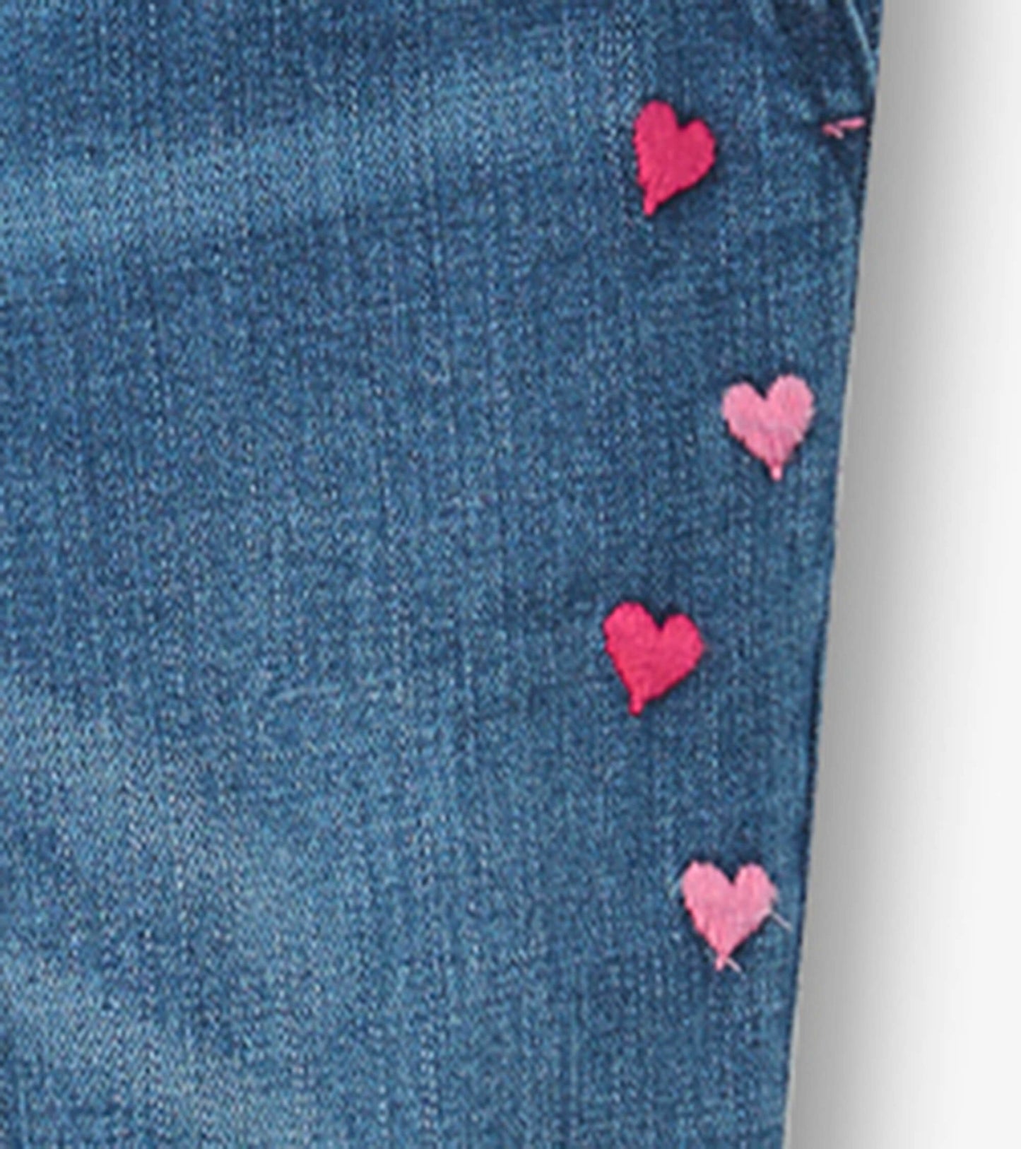 Denim overalls featuring embroidered pink hearts along the side, designed for girls.