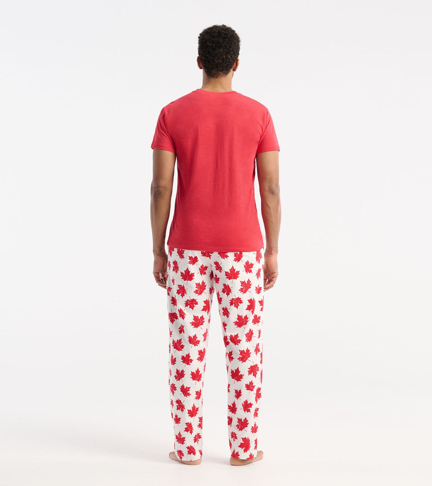 Red short-sleeve men's tee worn with white pants featuring red maple leaf patterns, viewed from the back.
