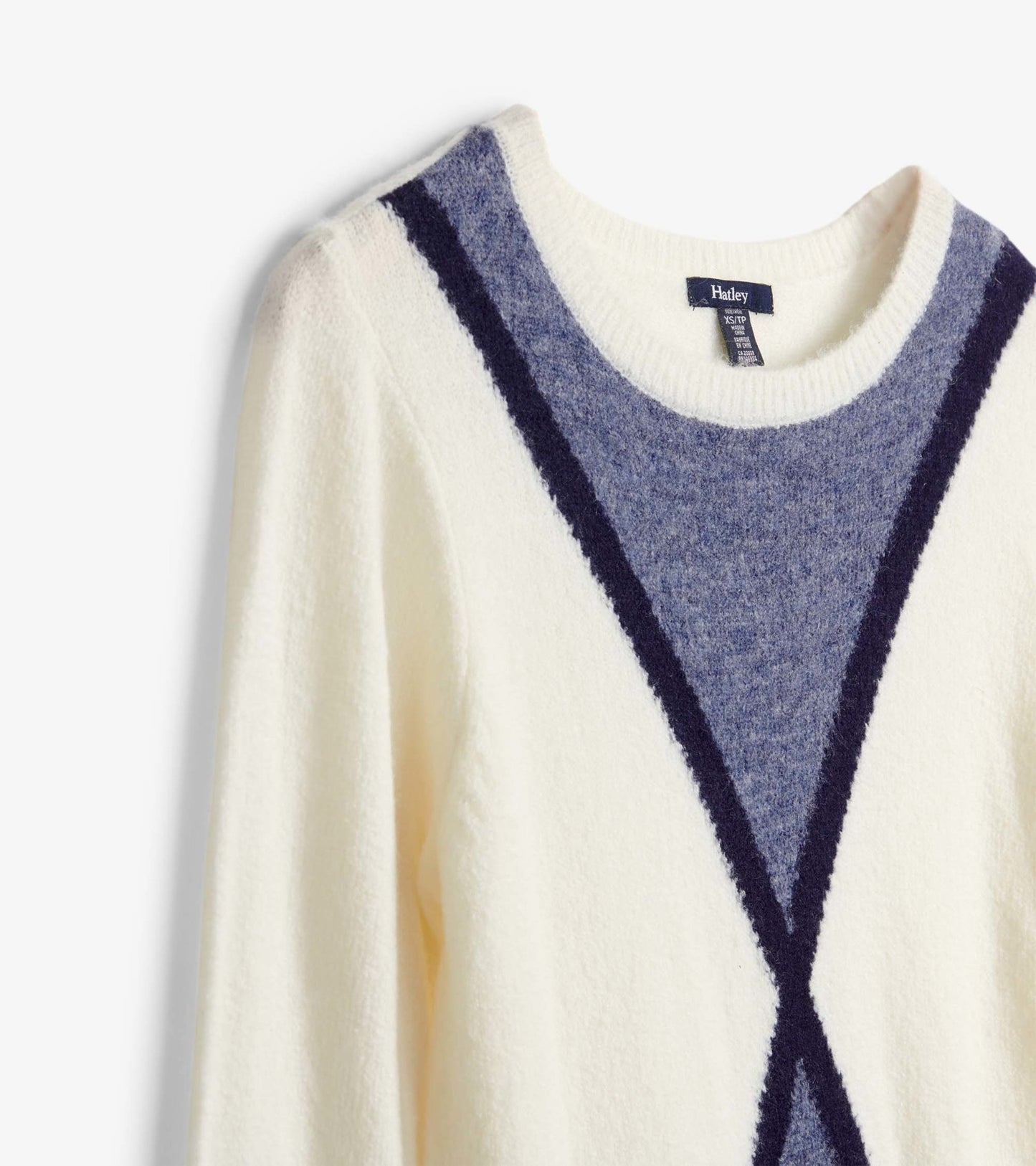 Cream sweater featuring a blue and navy geometric pattern, with a round neckline and long sleeves.