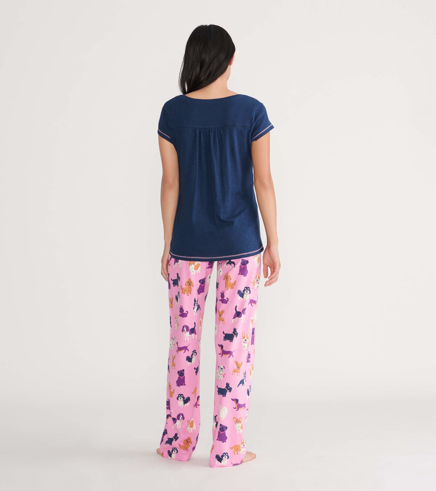 Navy blue women's V-neck tee with short sleeves, paired with colorful dog-patterned pajama pants, viewed from the back.