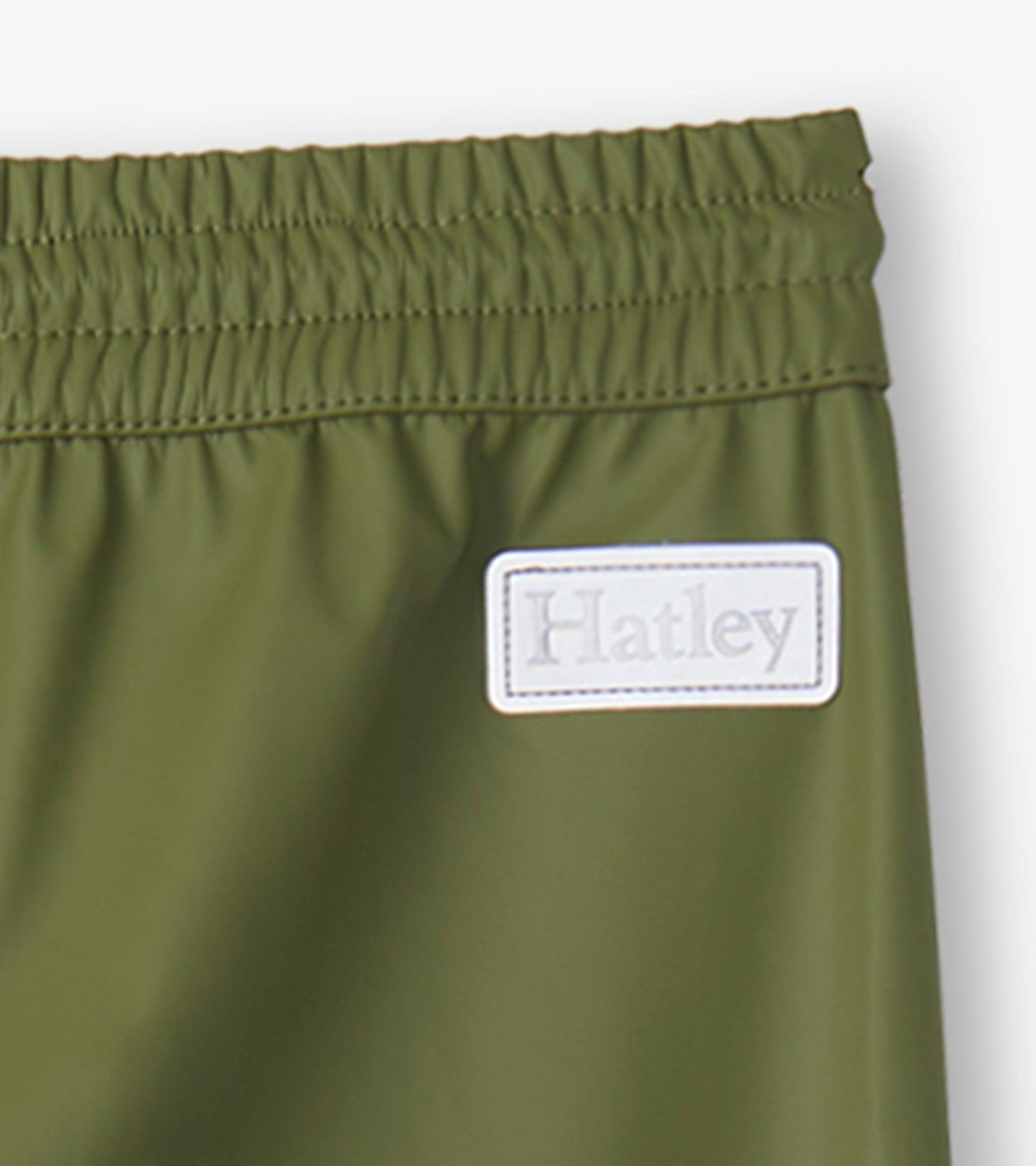 Forest green kids' rain pants with an elastic waistband and a small label. Ideal for outdoor play in wet weather.