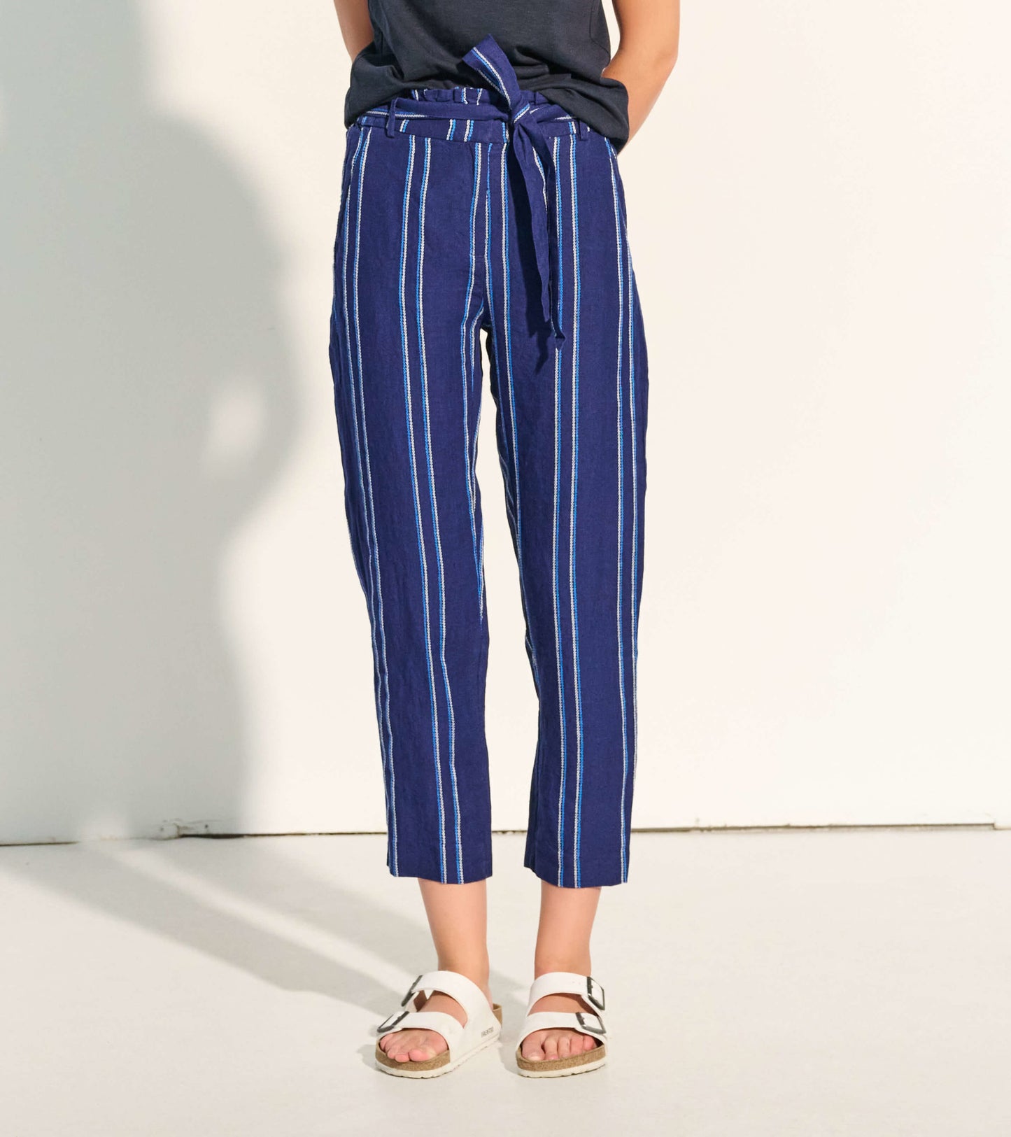 Navy paper bag pants with blue and white stripes, featuring a tie waist and cropped length, styled with a casual top.
