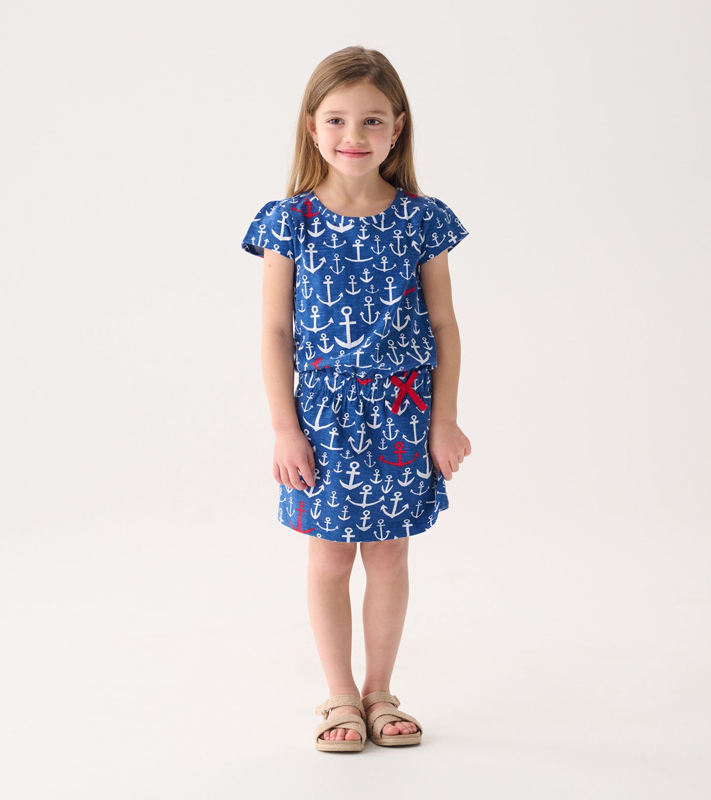 Blue t-shirt dress featuring a white and red anchor pattern, short sleeves, and an elastic waistband.