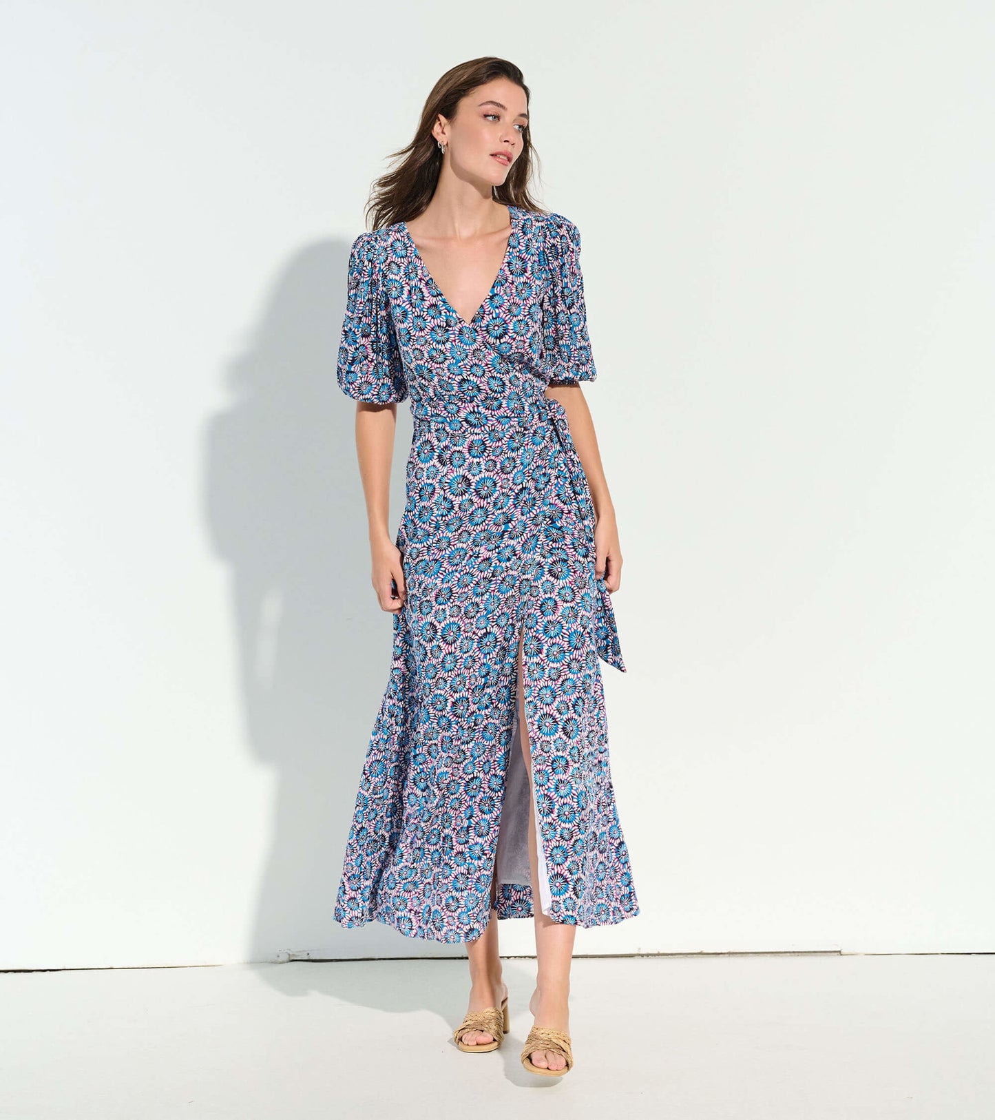 Blue wrap dress with a sundial mandala pattern, featuring puff sleeves and a side slit, styled with sandals.