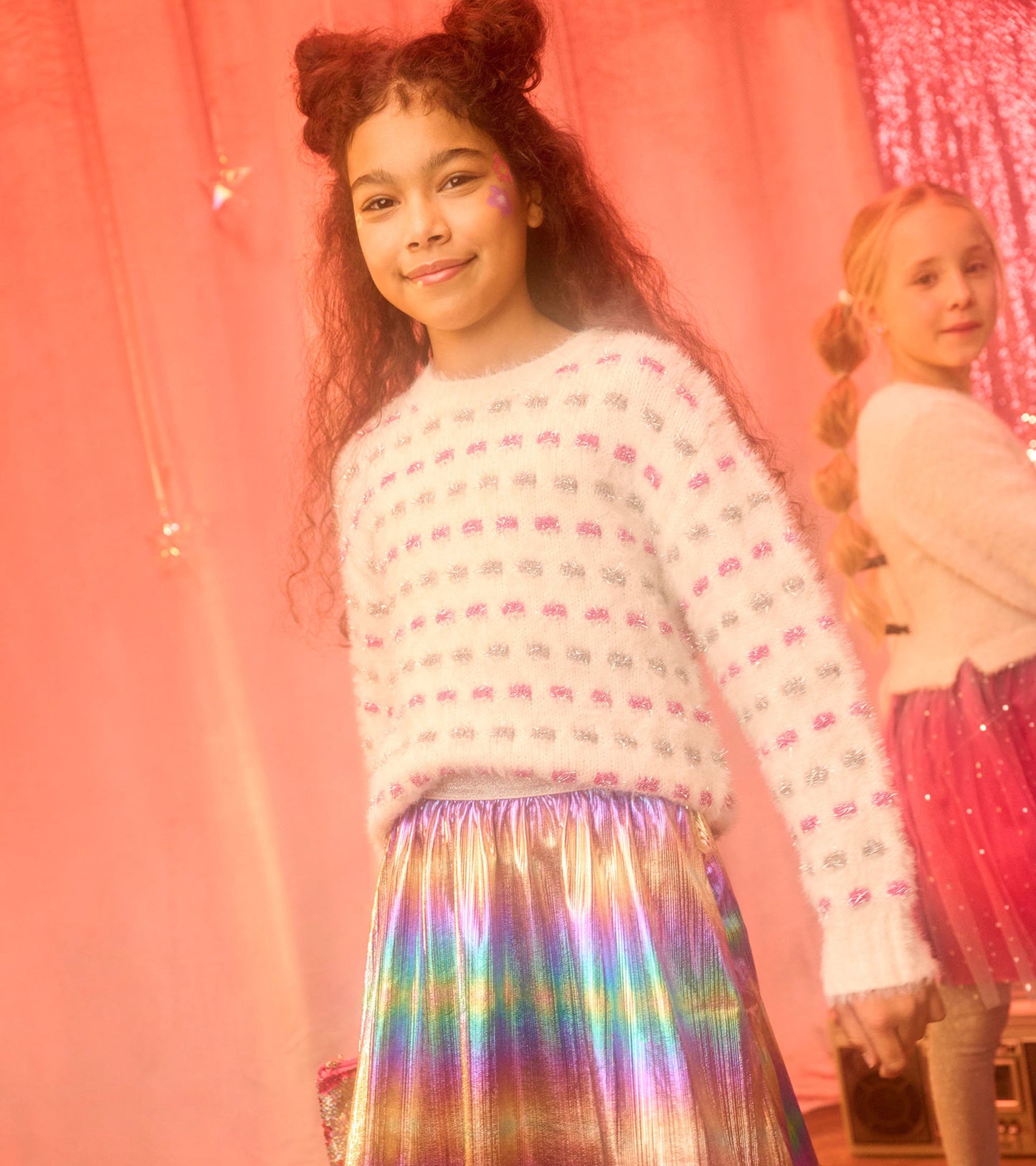 White sweater tunic with pink and silver woven dots, paired with a shiny, iridescent skirt.