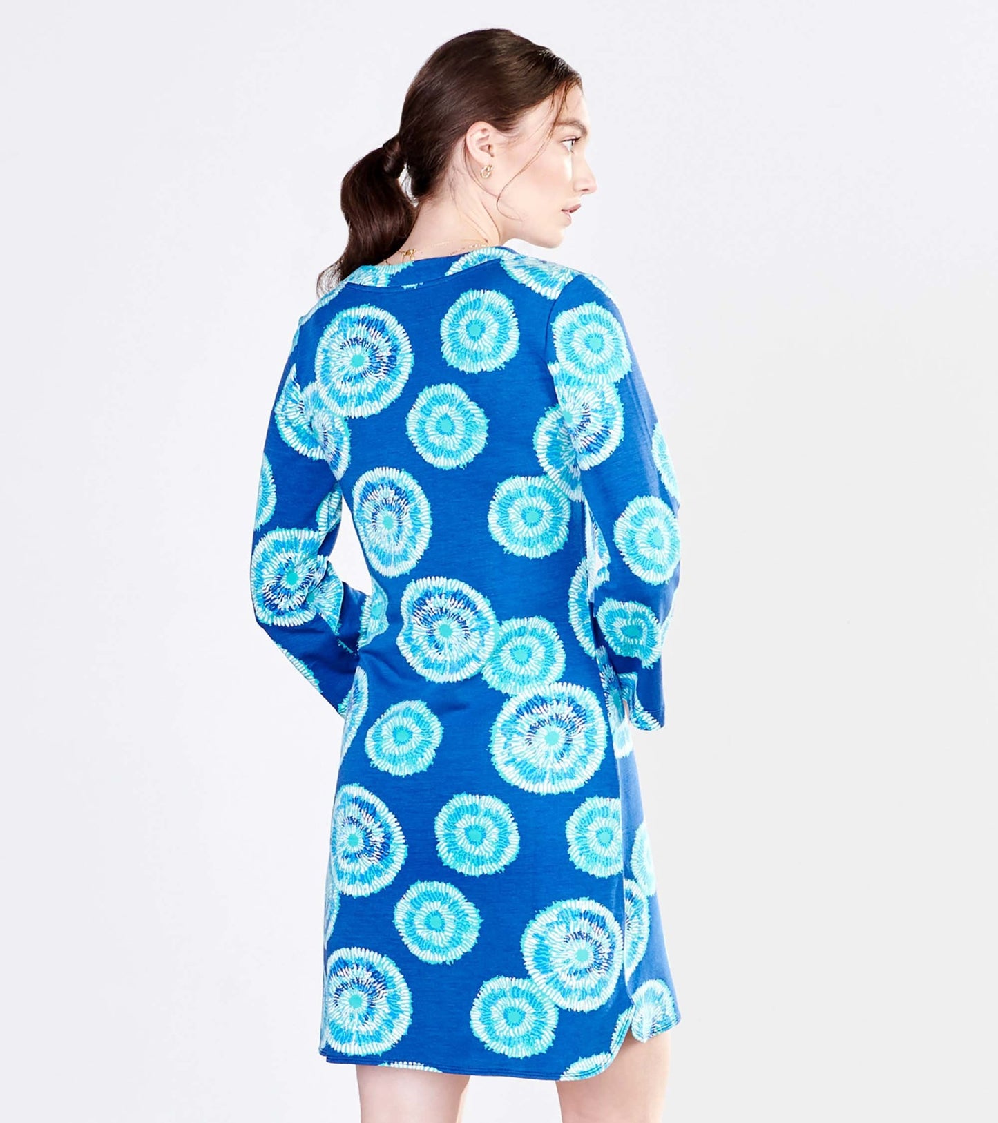 Blue dress featuring a vibrant sunburst pattern, long sleeves, and a relaxed fit, shown from the back.