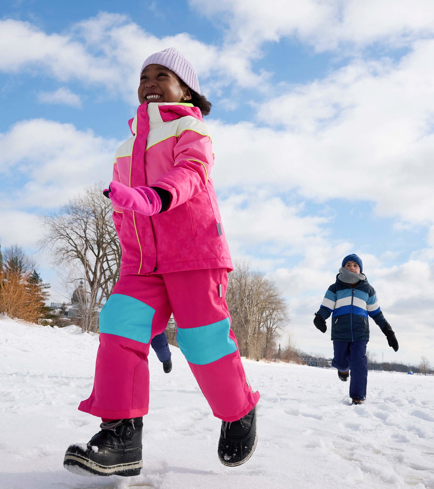 Bright pink snow pants with blue accents, designed for kids, suitable for winter activities in snowy conditions.