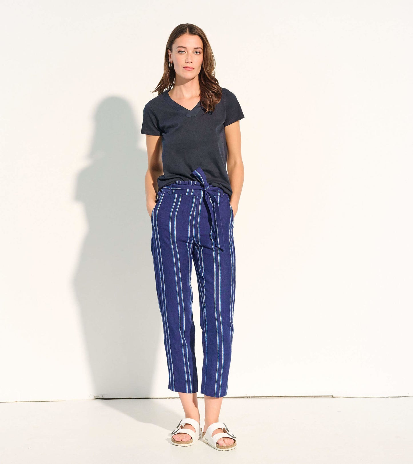 Navy paper bag pants with beach stripes, featuring a tie waist and cropped length, styled with a black v-neck top.