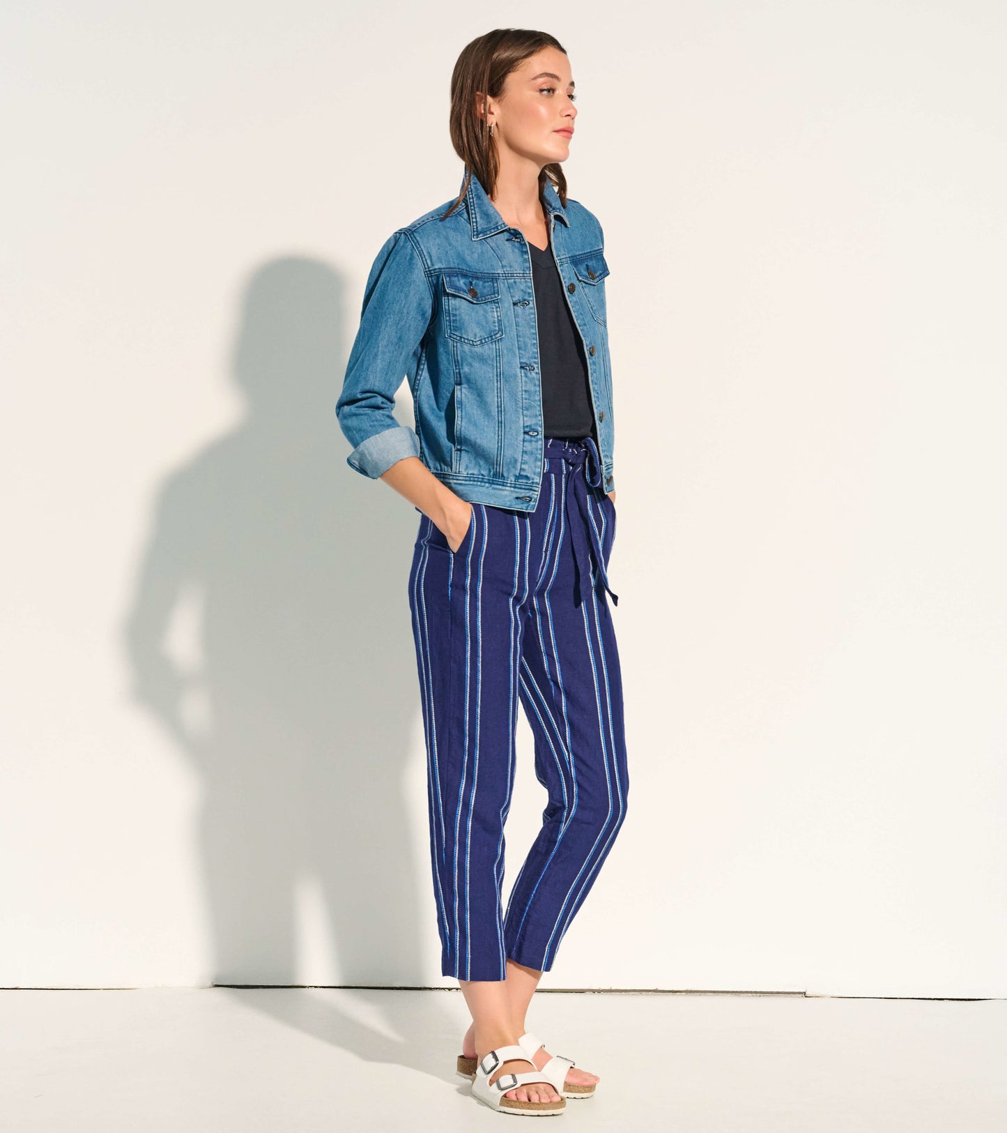 Light blue embroidered denim jacket with a fitted shape, worn over a black top and paired with striped pants.