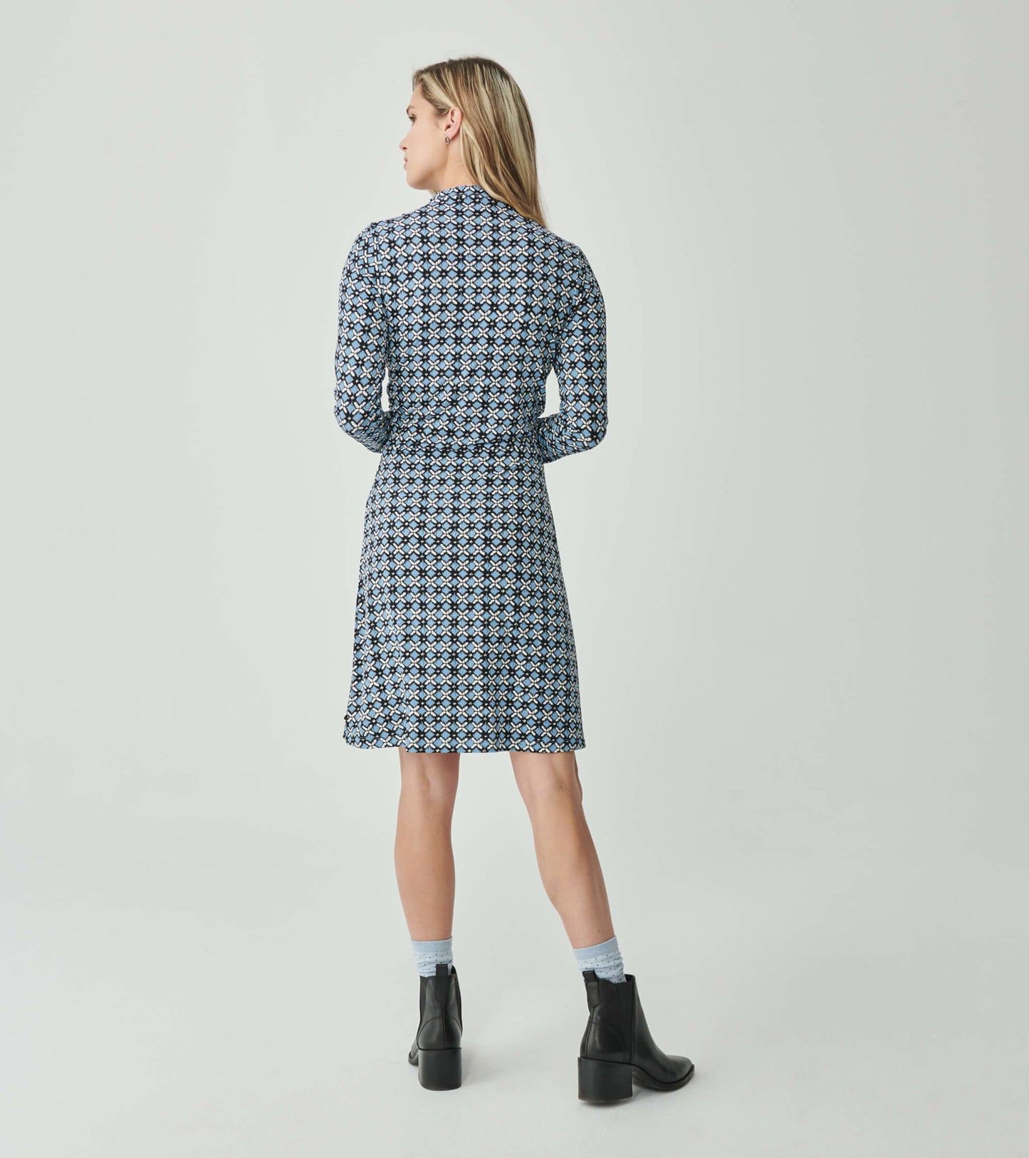Blue ikat-patterned dress with long sleeves and a fitted waist, shown from the back, paired with ankle boots.