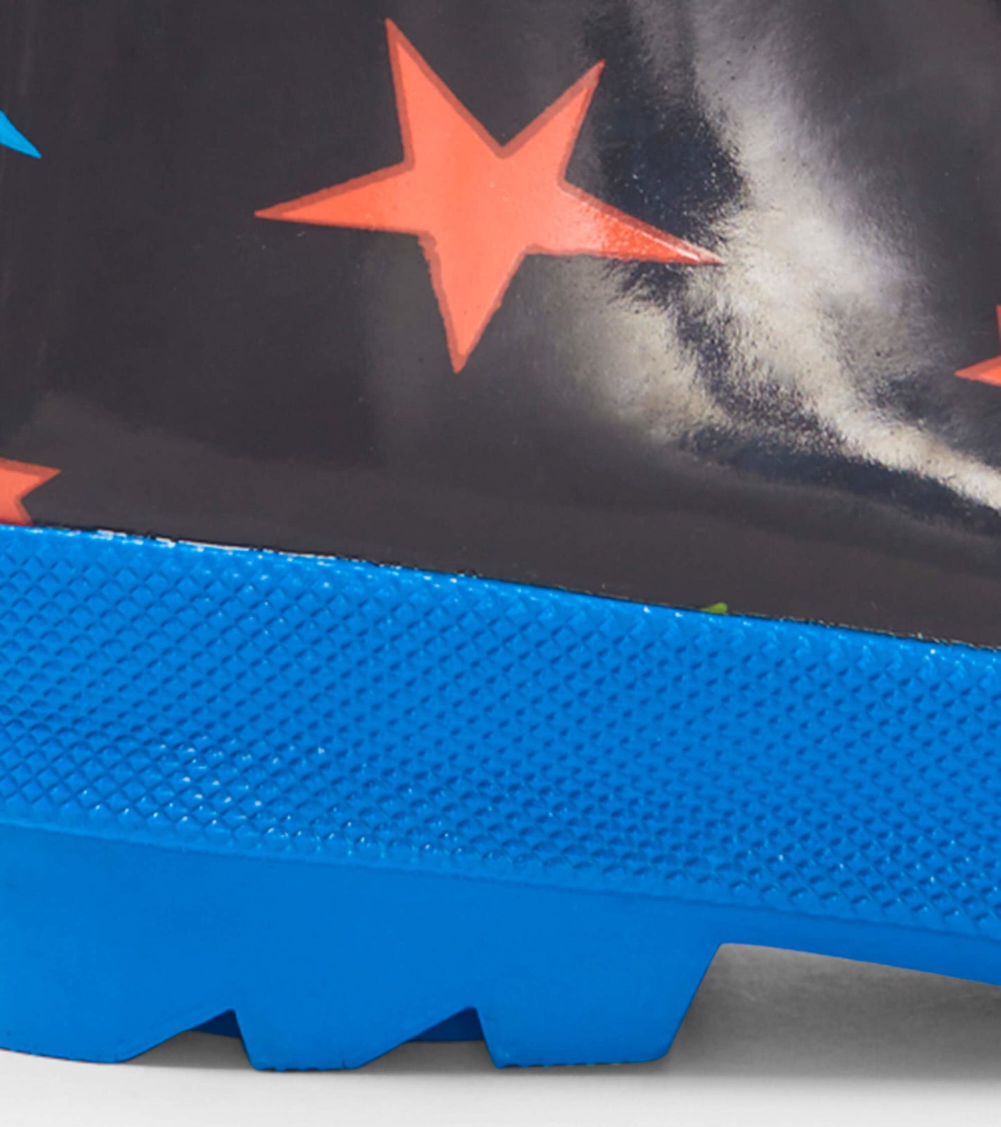 Shiny black rain boots with colorful stars and a blue textured sole, designed for kids.