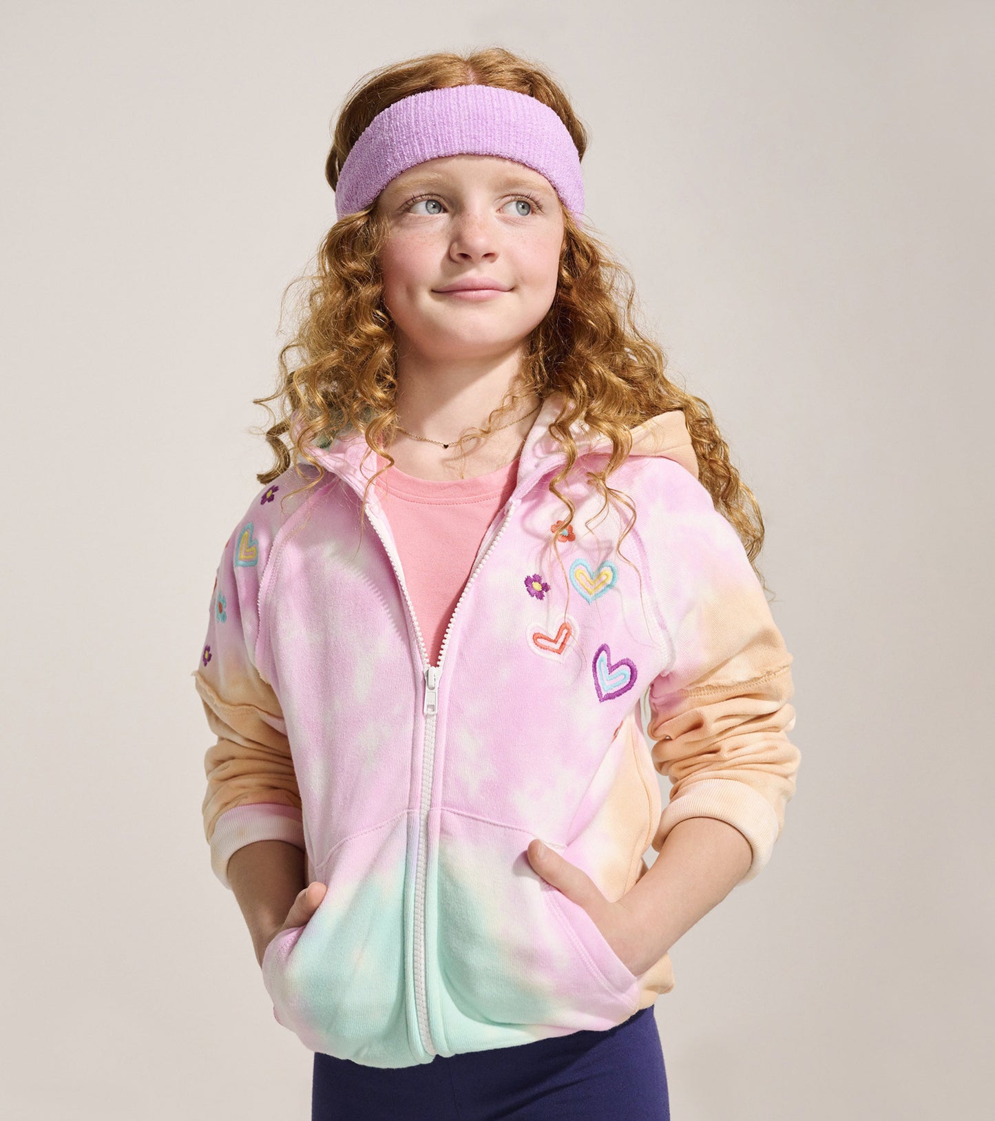 Tie-dye hoodie in pastel colors with heart and flower embroidery, featuring a zip front and pockets.