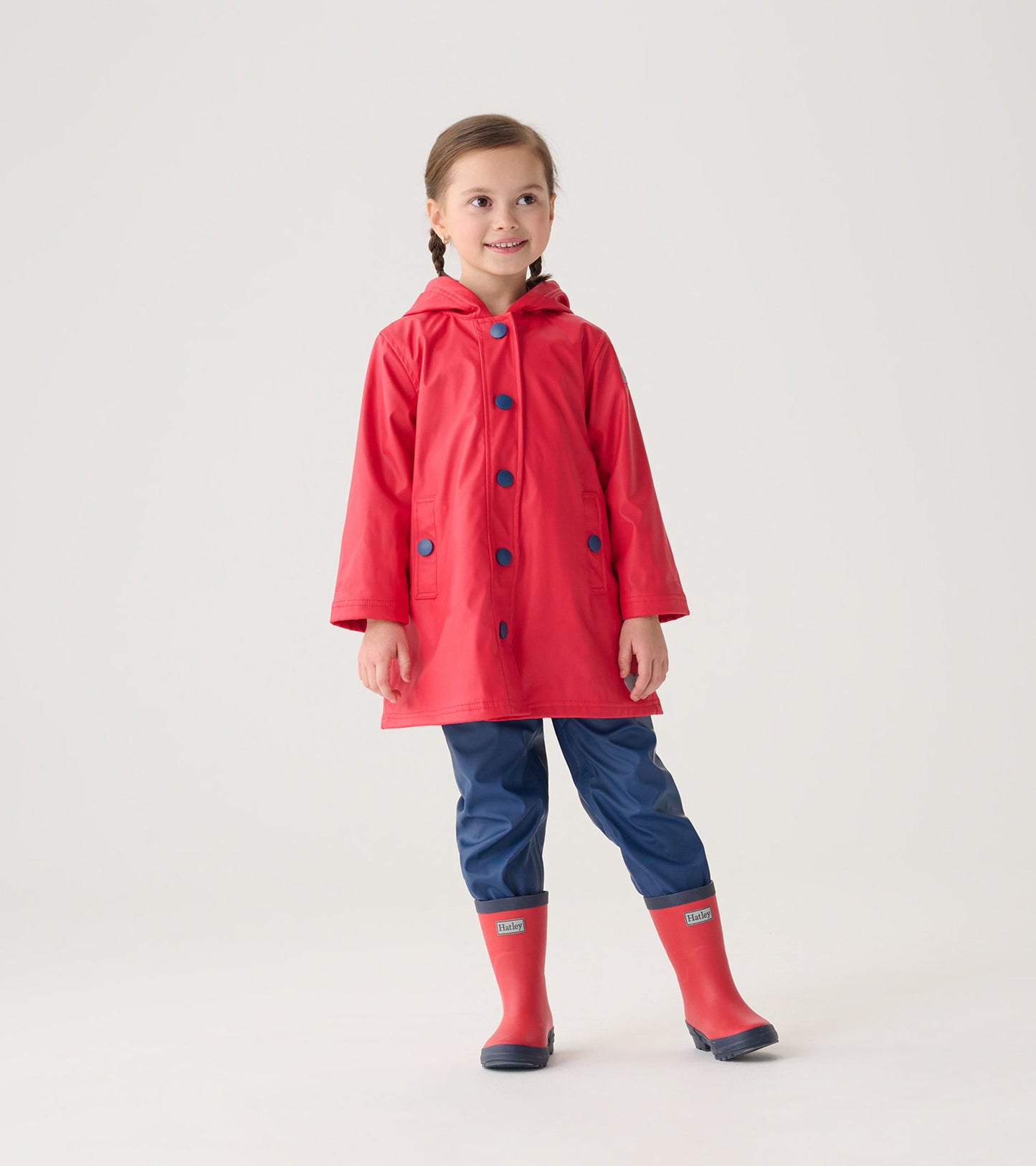 Red and navy button-up rain jacket with a hood, featuring blue buttons and pockets, worn by a smiling girl.