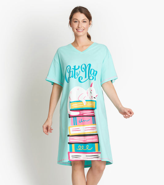 A light blue sleepshirt featuring a playful cat design resting on colorful stacked books. V-neck and short sleeves.